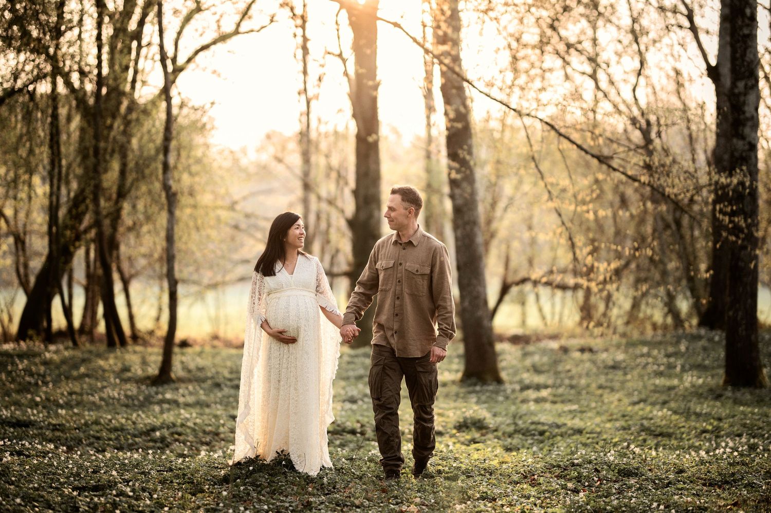 Gravid kvinna och hennes partner delar en kärleksfull stund under en gravidfotografering i skogen.