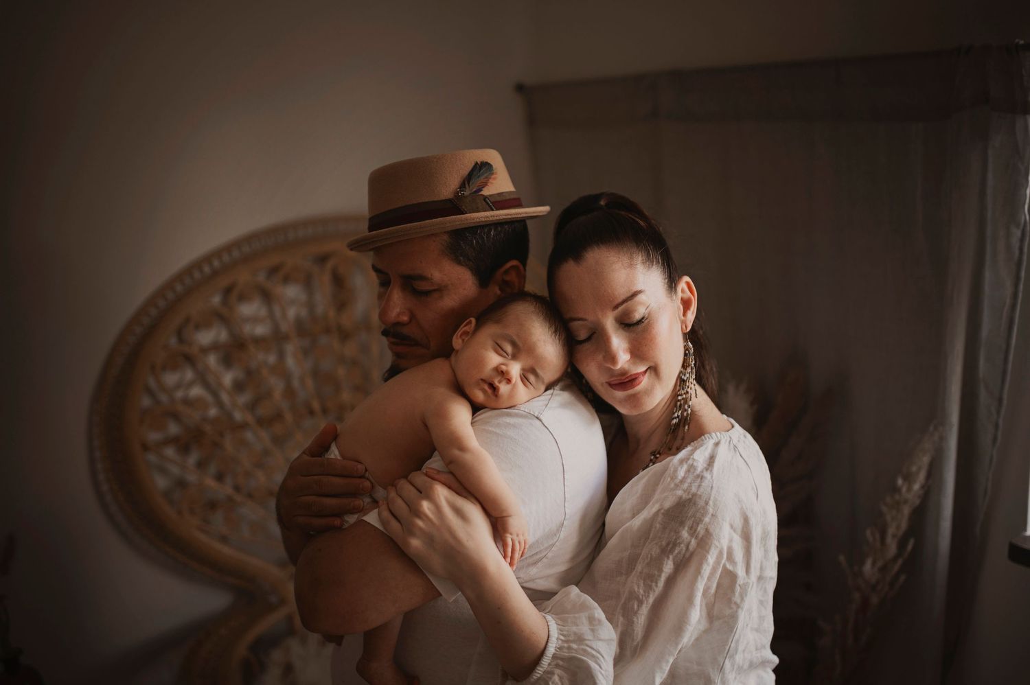 A tender moment between parent and baby in a dimly lit room with a decorative circular backdrop.