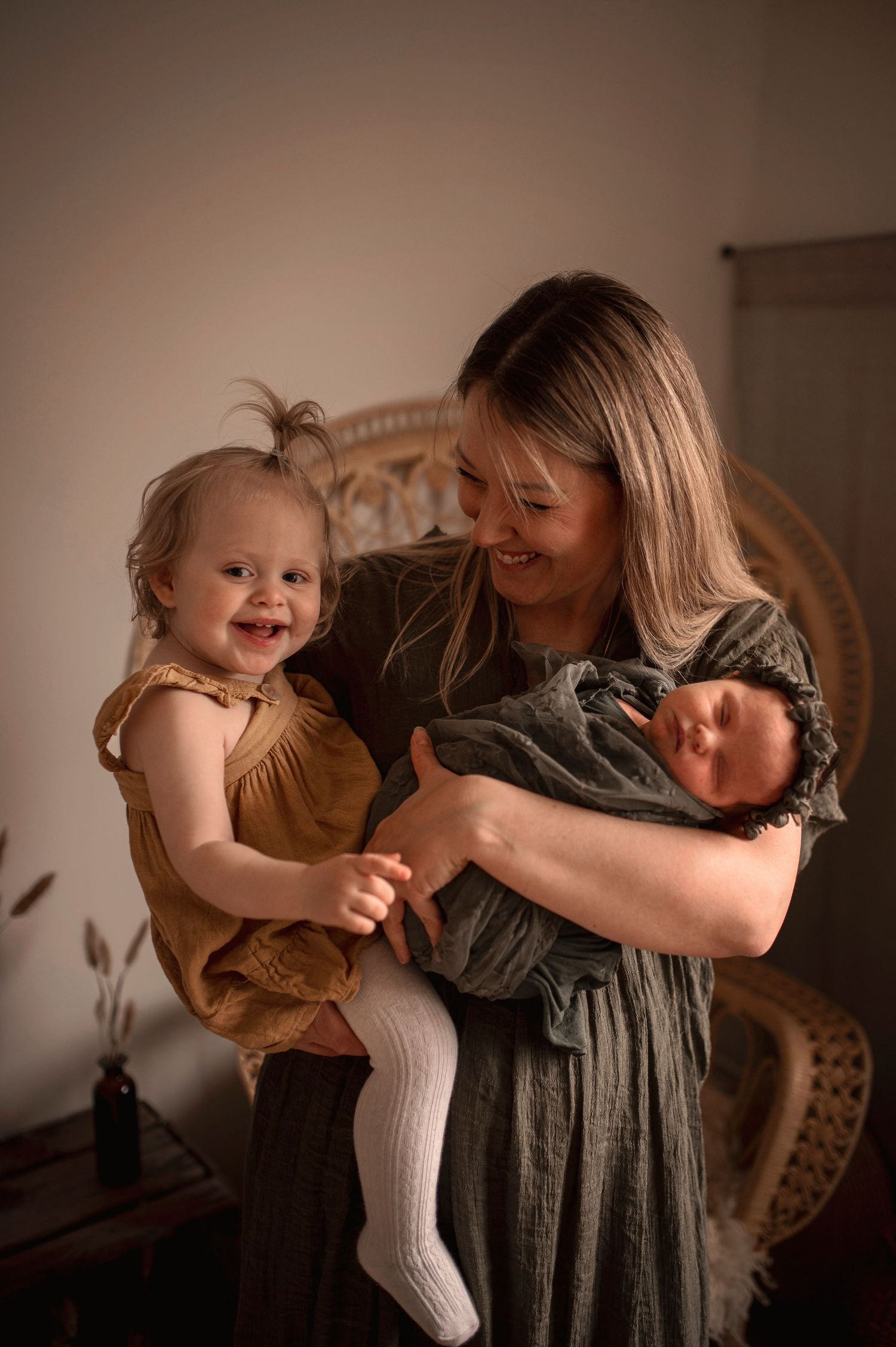 Familjefotografering i Hässleholm med mamma, syskon och nyfödd bebis i varm studiomiljö.