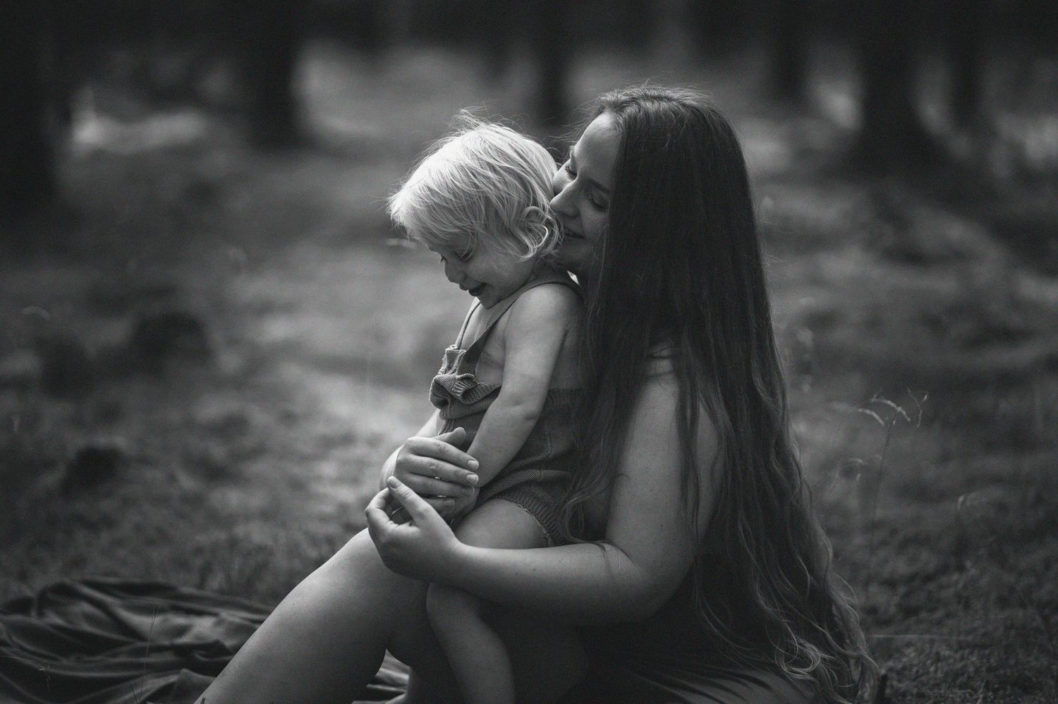 familjefotografering i Skåne med intimt ögonblick mellan förälder och barn i skogsmiljö.