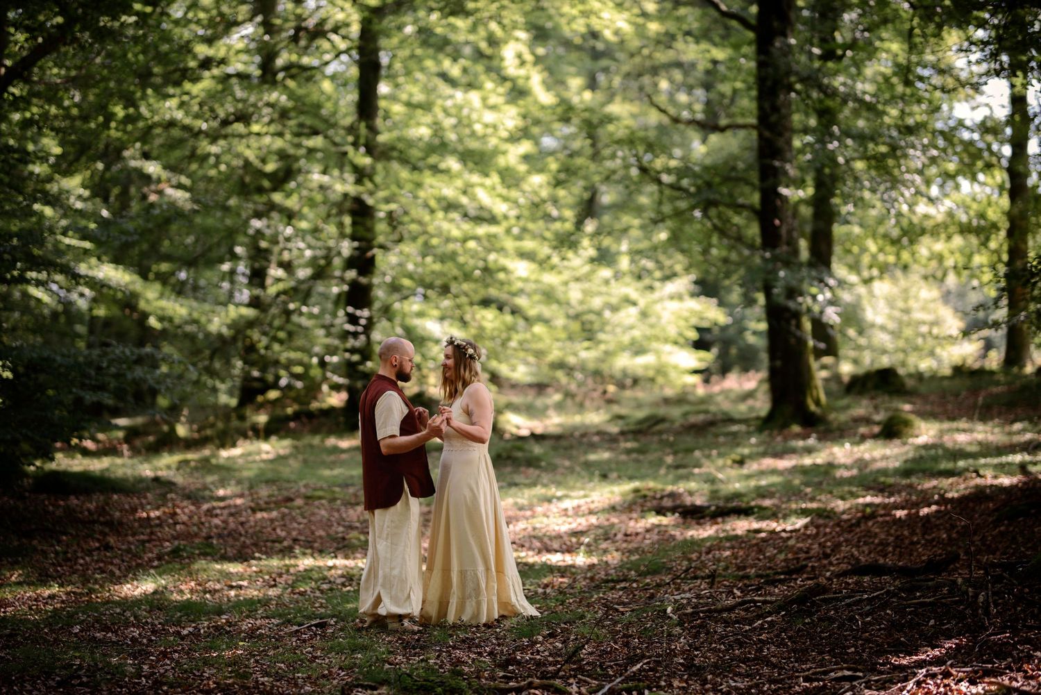 Bride and groom sharing a tender moment together in a sunlit forest clearing.