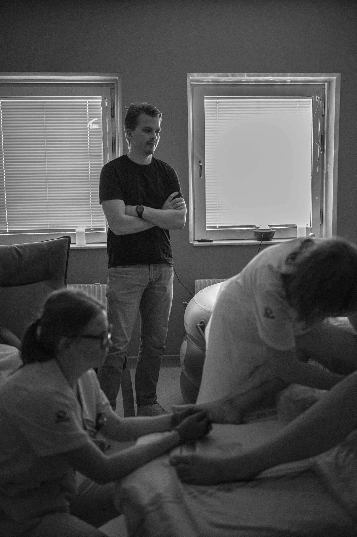 A black and white image showing a classroom setting with students gathered around a massage table during instruction.