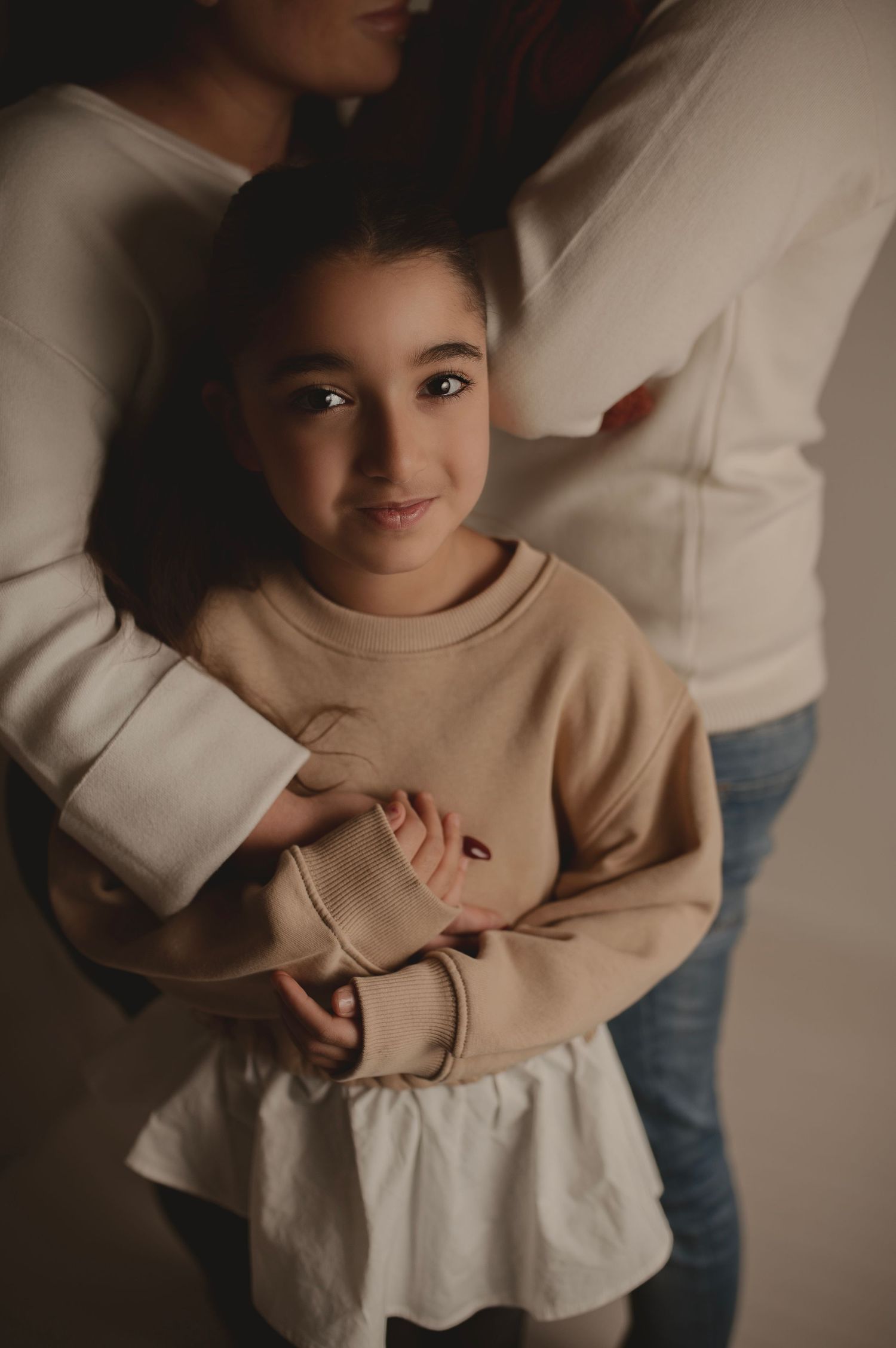 Portrait of person in beige sweater and white skirt smiling warmly.