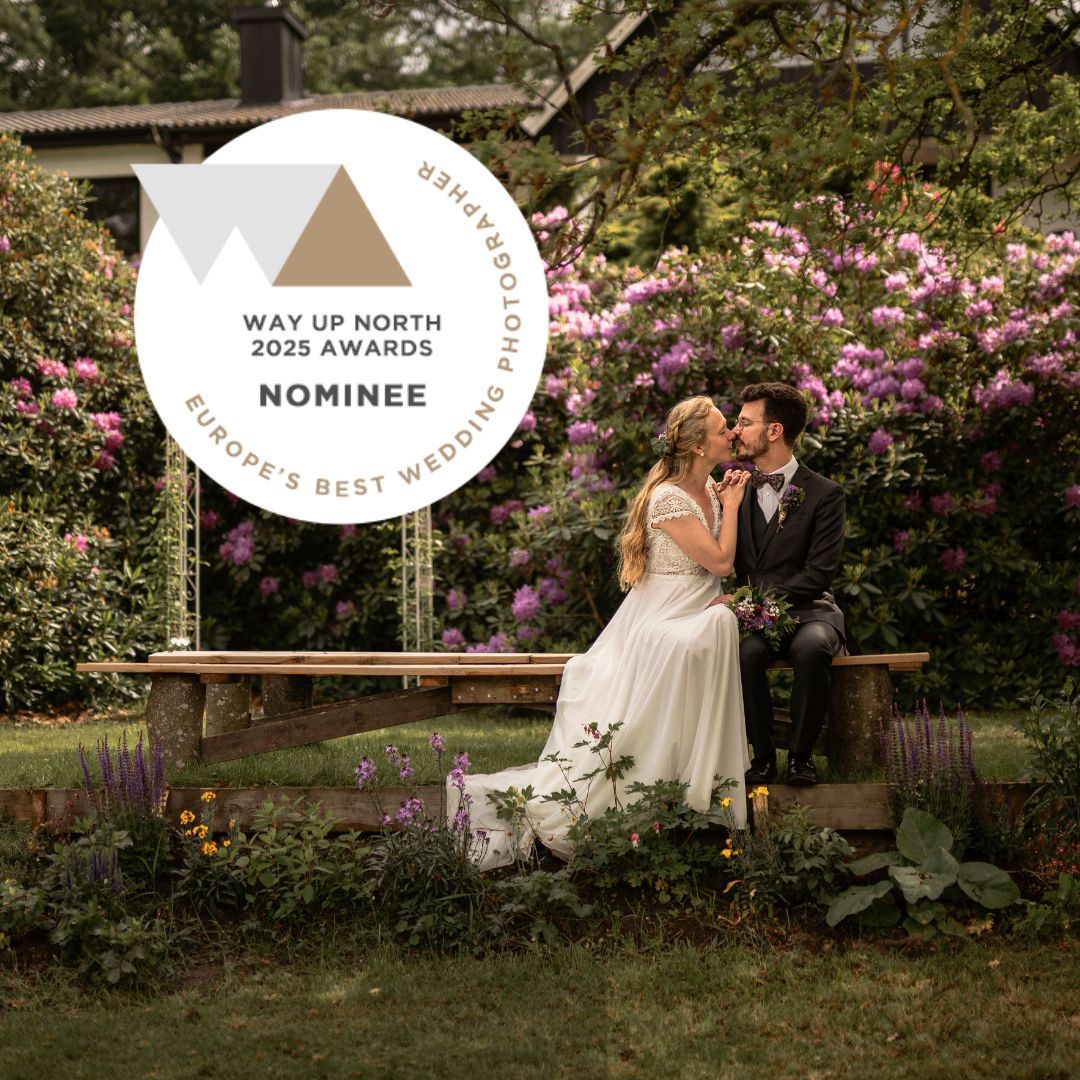 Brudpar kysser varandra i en blomstrande trädgård. Fotografen nominerad till Way Up North Europe's Best Wedding Awards 2025.