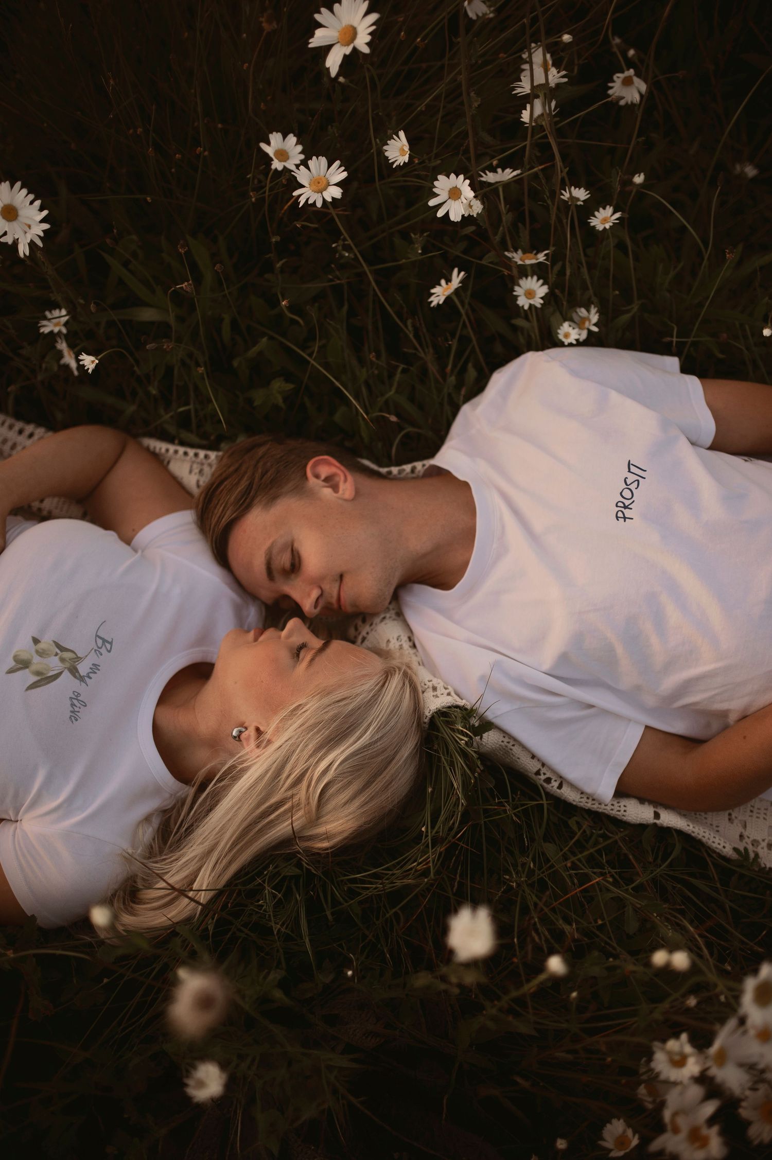Gravidfotografering i Skåne med blivande föräldrar i blomsteräng i mjukt kvällsljus.