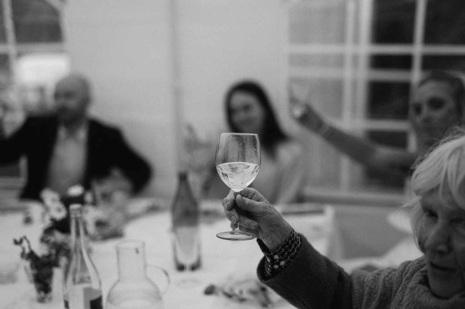 Eventfotografering i Skåne med gäster som skålar under elegant middag i svartvitt ljus.