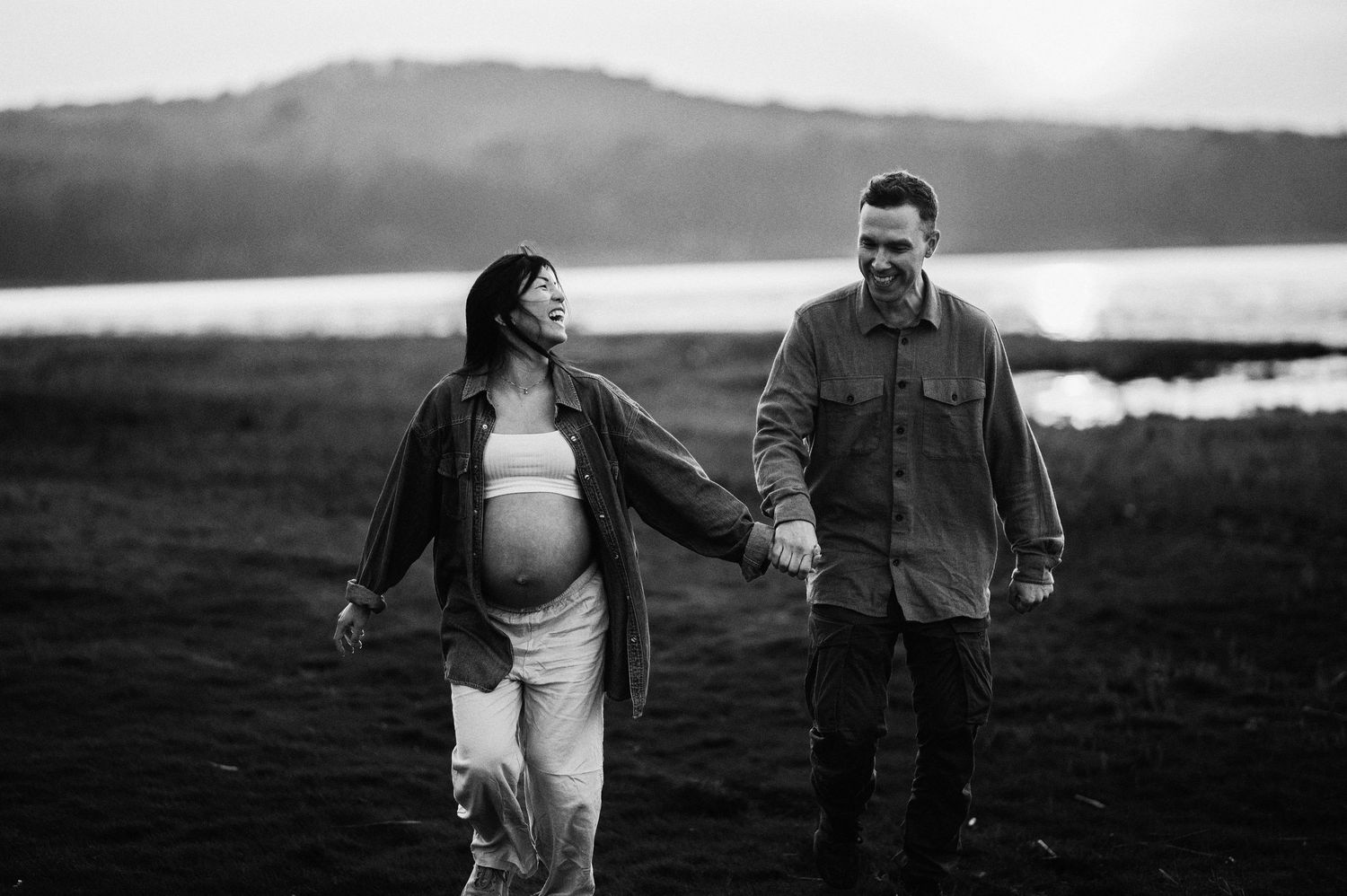 Svartvit parfotografering i Skåne med ett par som promenerar och omfamnar varandra i naturen