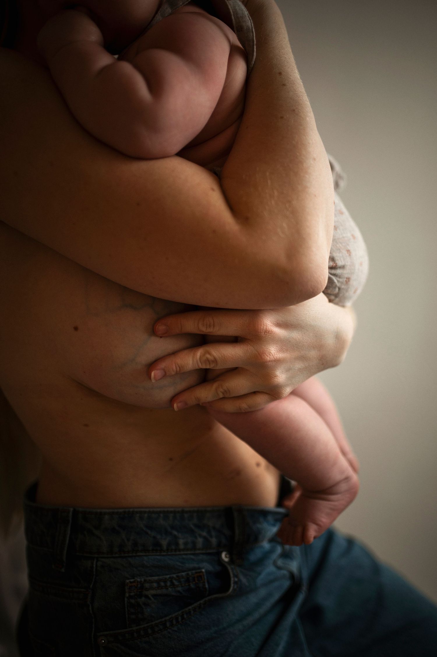 Nyföddfotografering i Hässleholm med mamma och nyfödd bebis i mjukt naturligt ljus i hemmalik miljö.