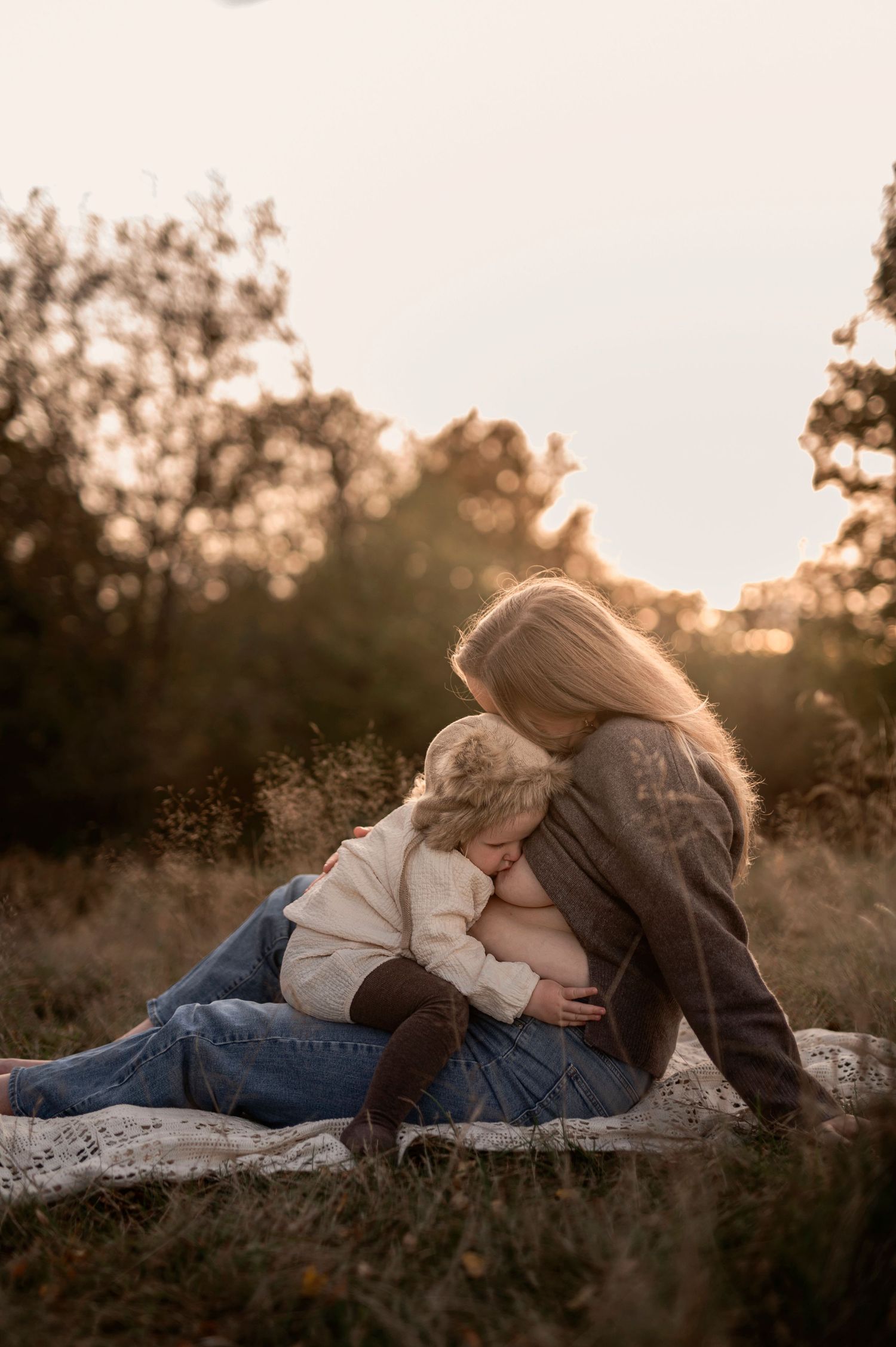 Amningsfotografering i Skåne med mamma och bebis i mjukt naturligt ljus i utomhusmiljö.