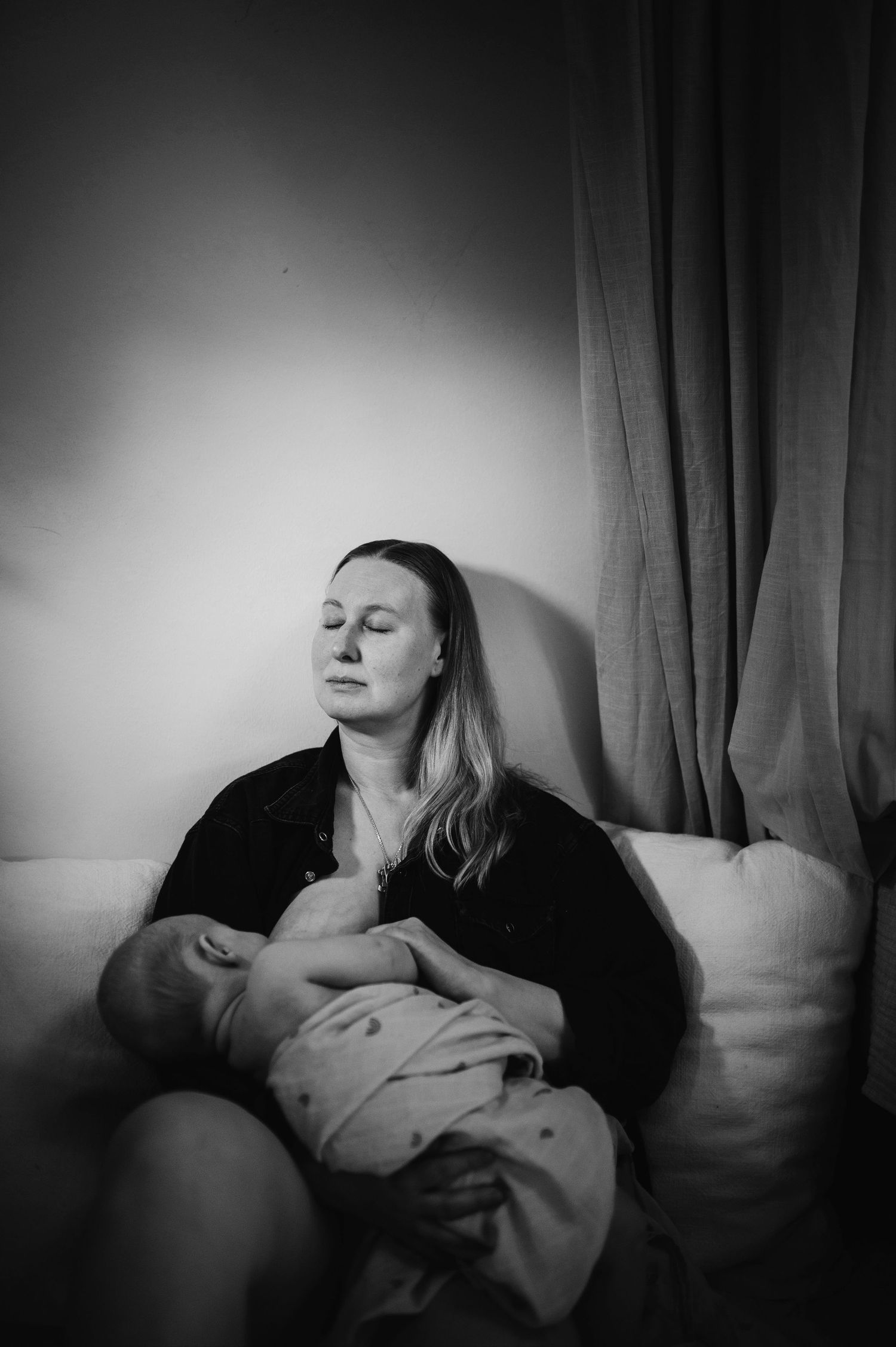 Svartvit nyföddfotografering i Hässleholm med mamma och bebis i hemmiljö i en intim stund.