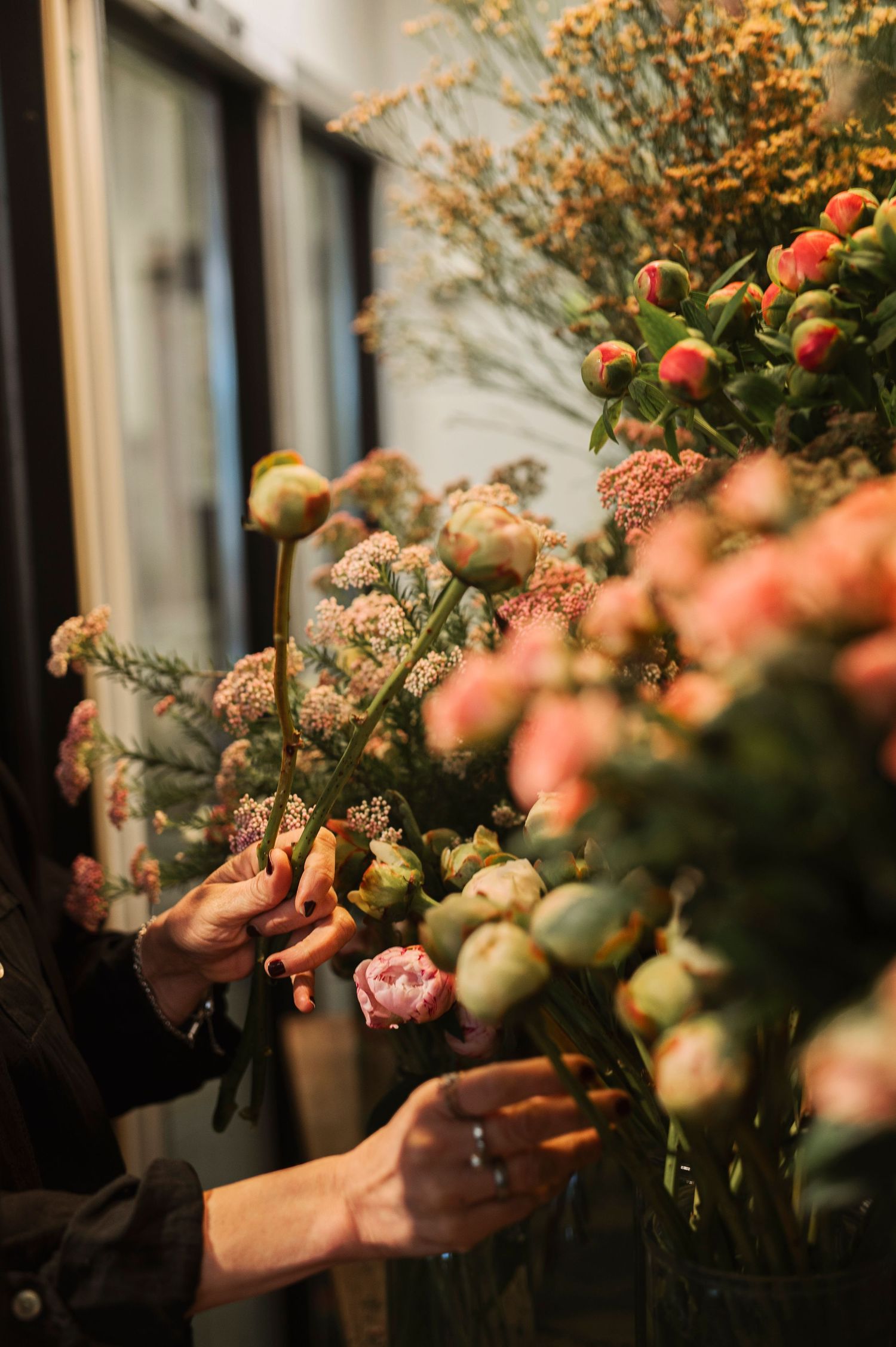 Företagsfotografering i Skåne med florist som arrangerar pioner och vilda blommor i blomsterbutik.