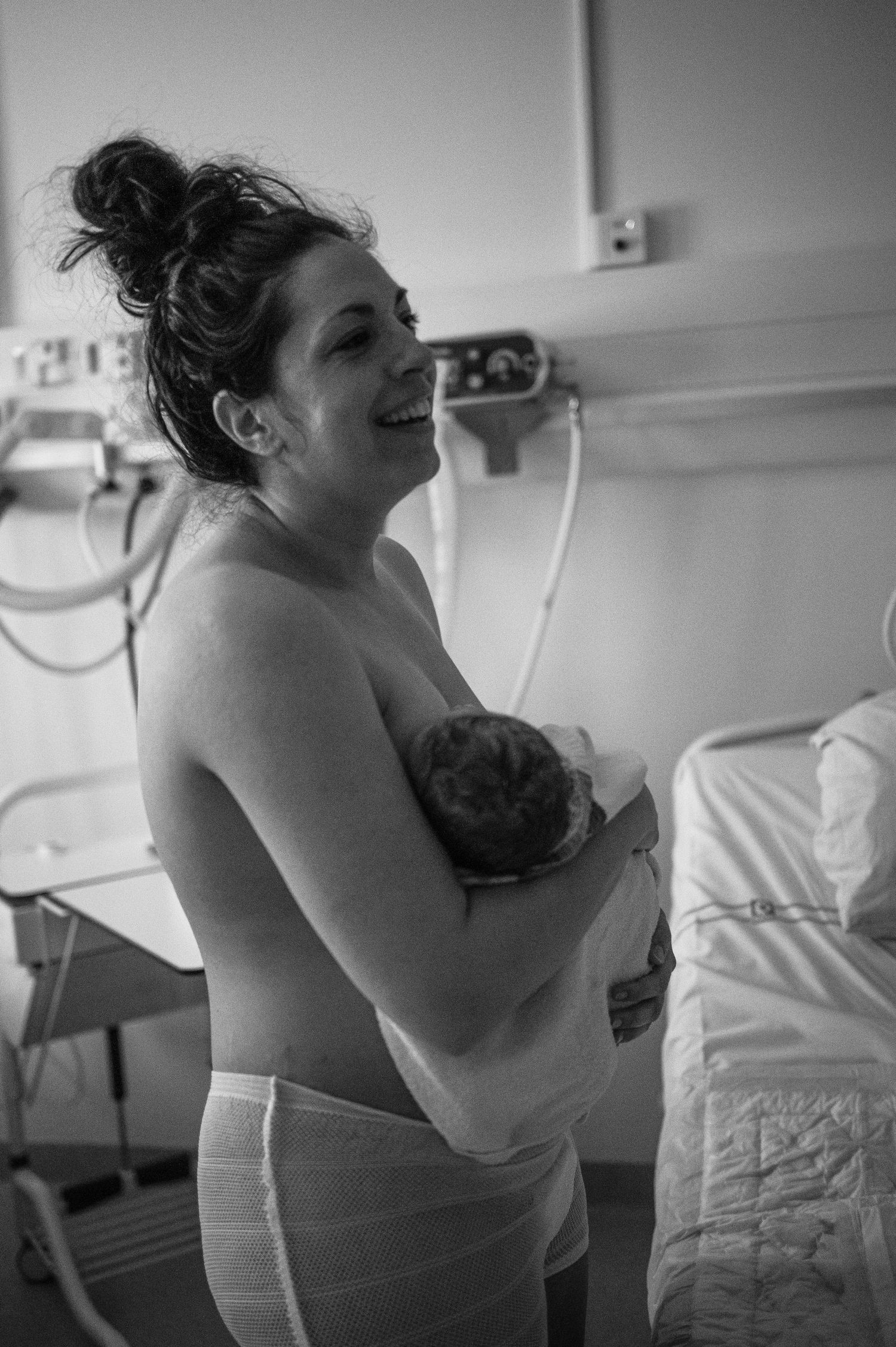 A joyful moment captured in black and white as a newborn baby is held against their mother's chest.