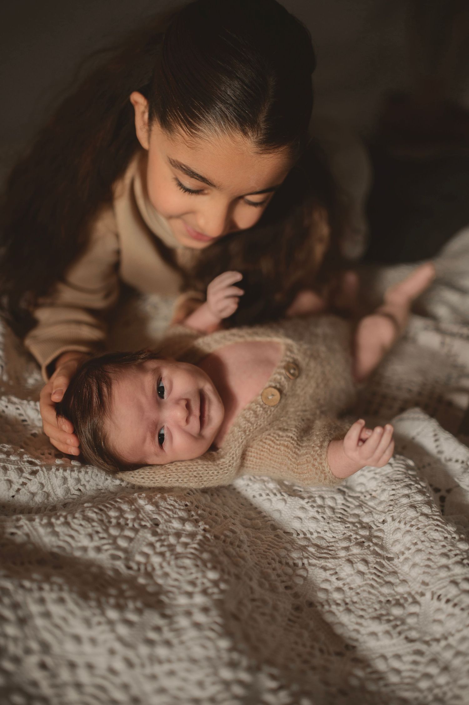 Sweet candid moment between caregiver and baby on lace textured bedding.