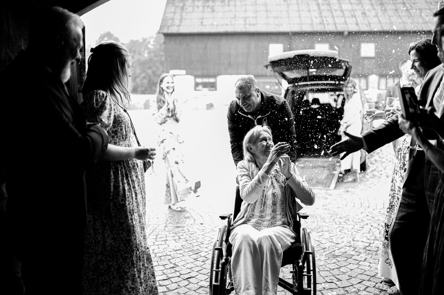 Bröllopsfotografering i Skåne med känslosam hyllning under utomhusvigsel med konfetti och gäster.