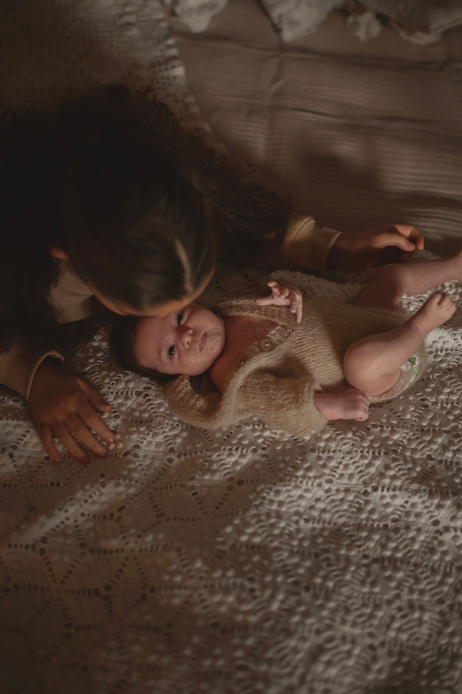 Gentle interaction captured in warm tones on textured blanket.
