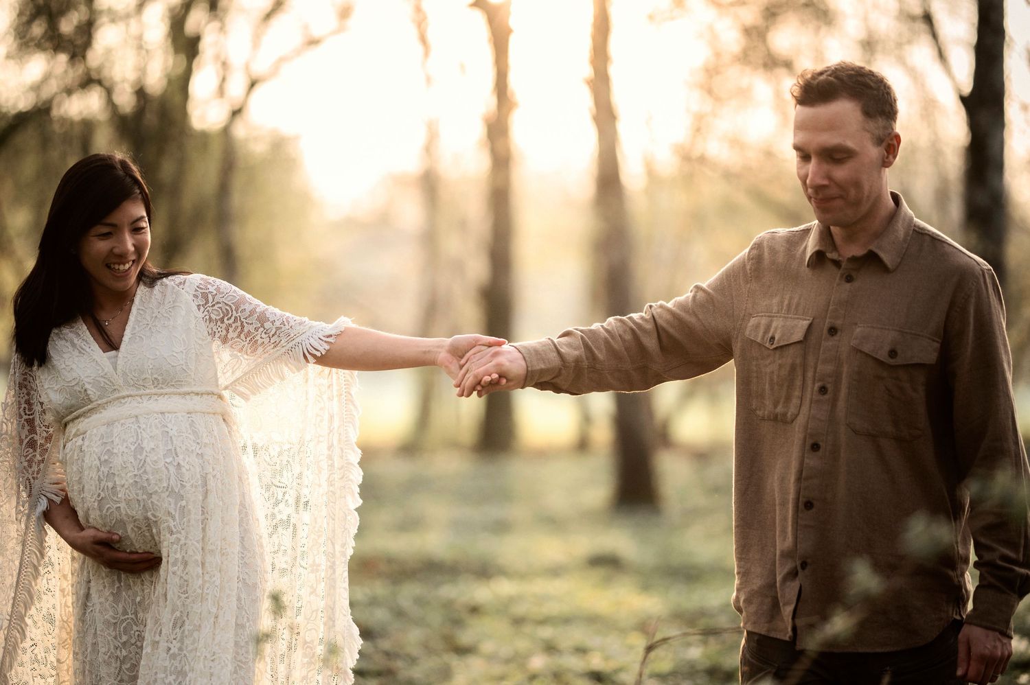 Gravid kvinna och hennes partner delar en kärleksfull stund under en gravidfotografering i skogen.