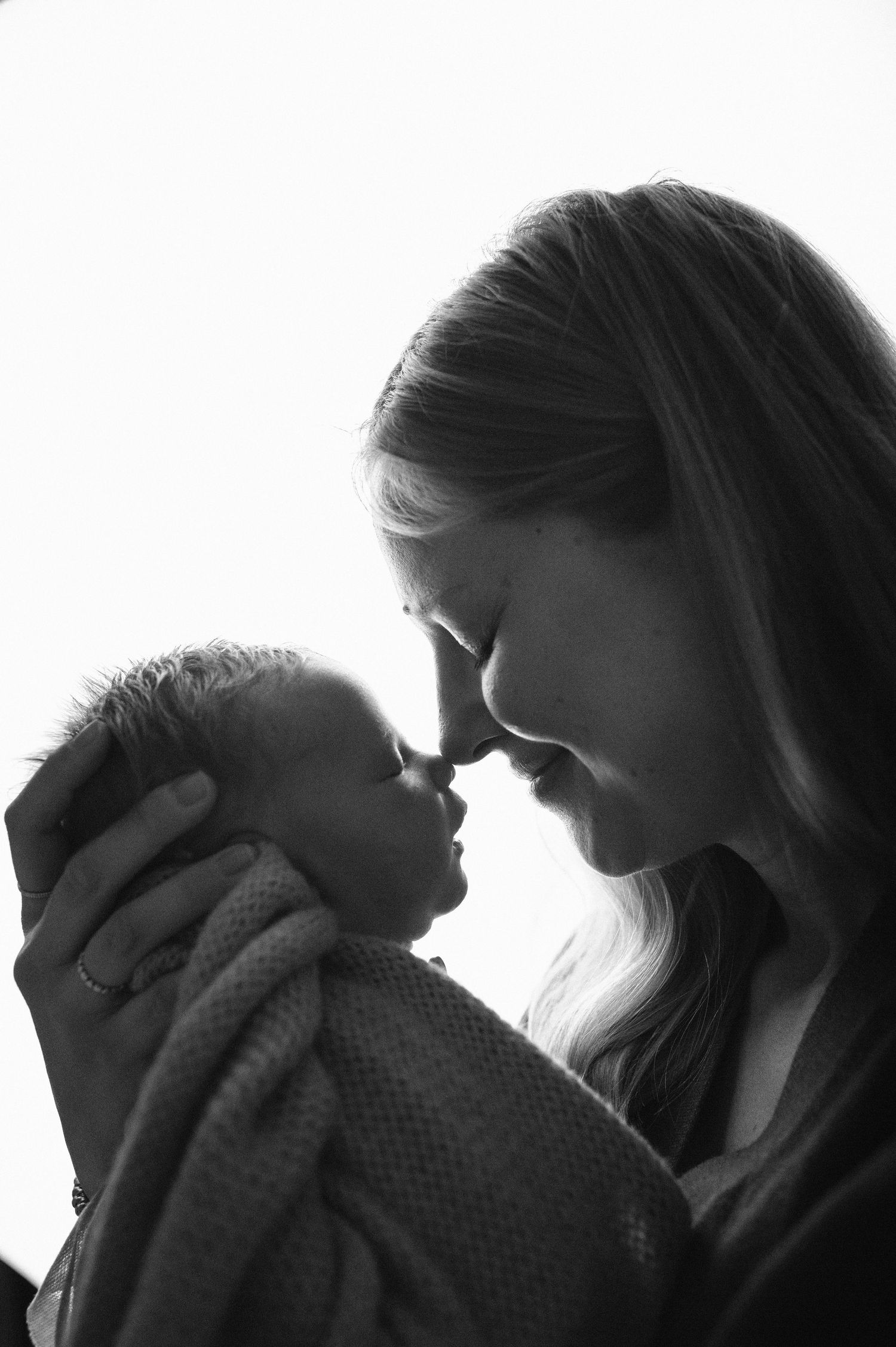 Svartvit nyföddfotografering i Hässleholm med mamma som möter sitt nyfödda barn i en kärleksfull stund.