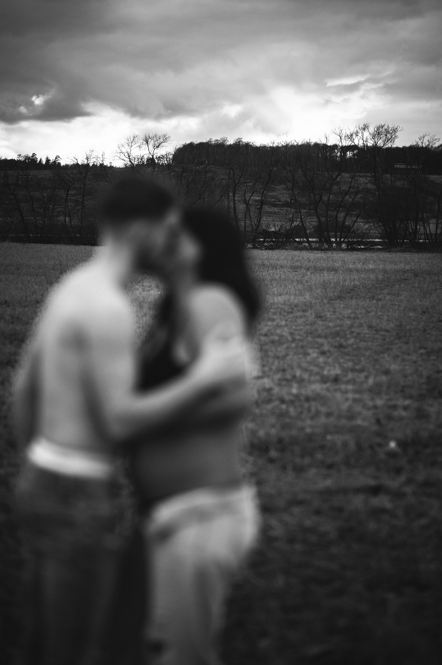 A soft focus black and white maternity photo with a moody landscape backdrop.