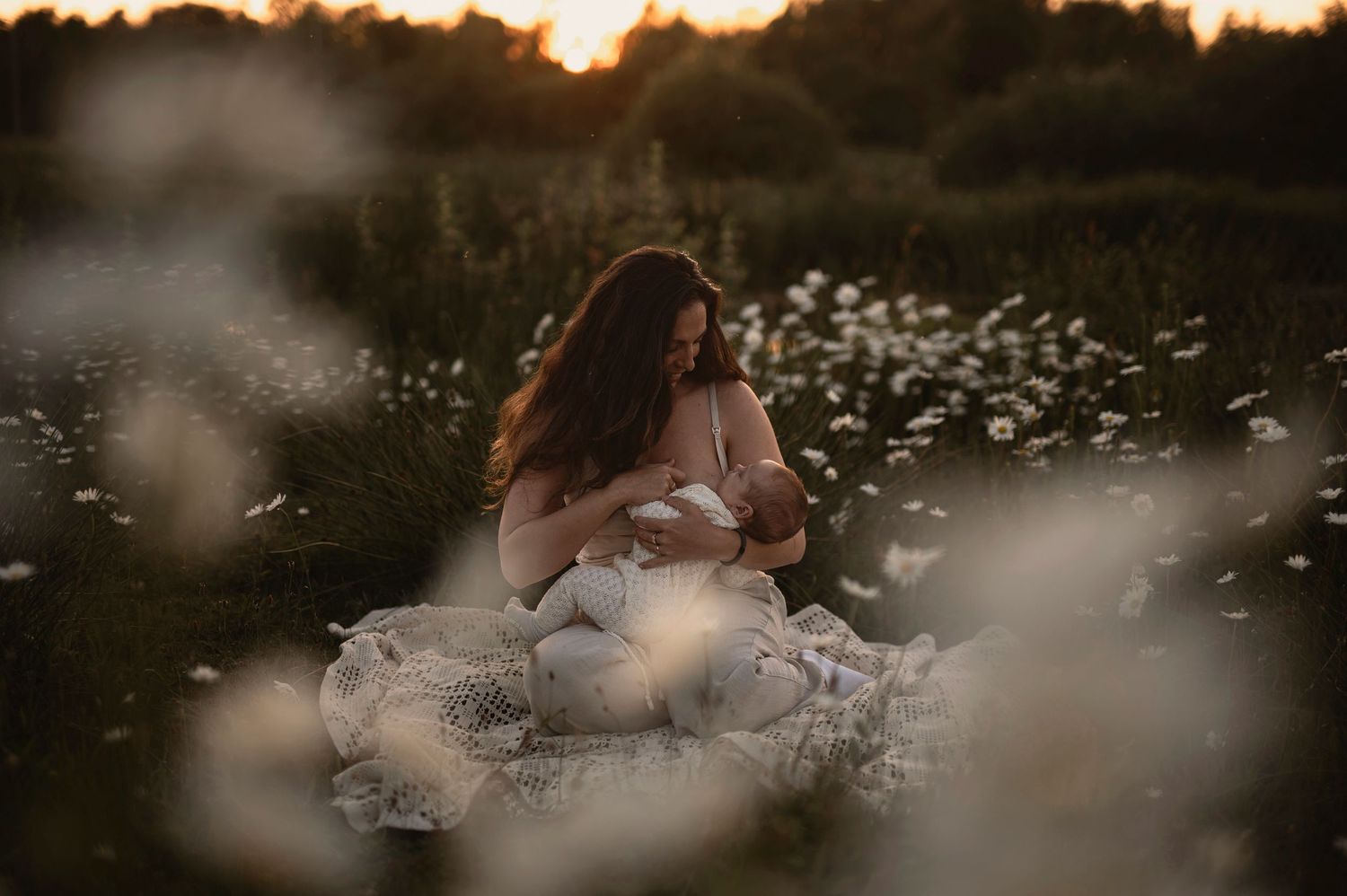 Amningsfotografering i Skåne med mamma och bebis i tusenskönaäng i solnedgång.