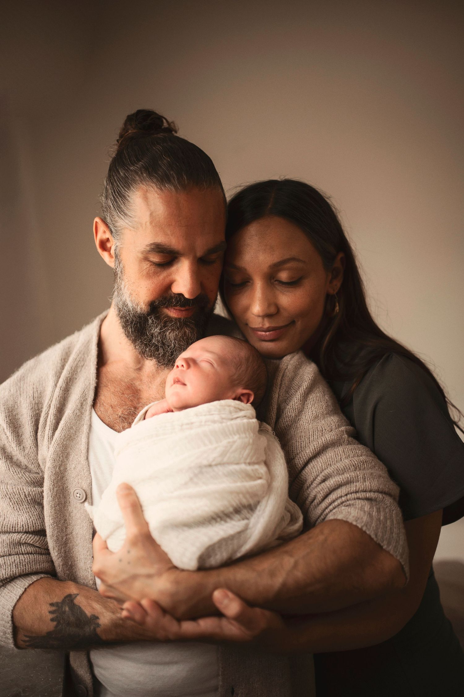 Nyföddfotografering i Hässleholm med föräldrar och deras sovande bebis i en varm studiomiljö.