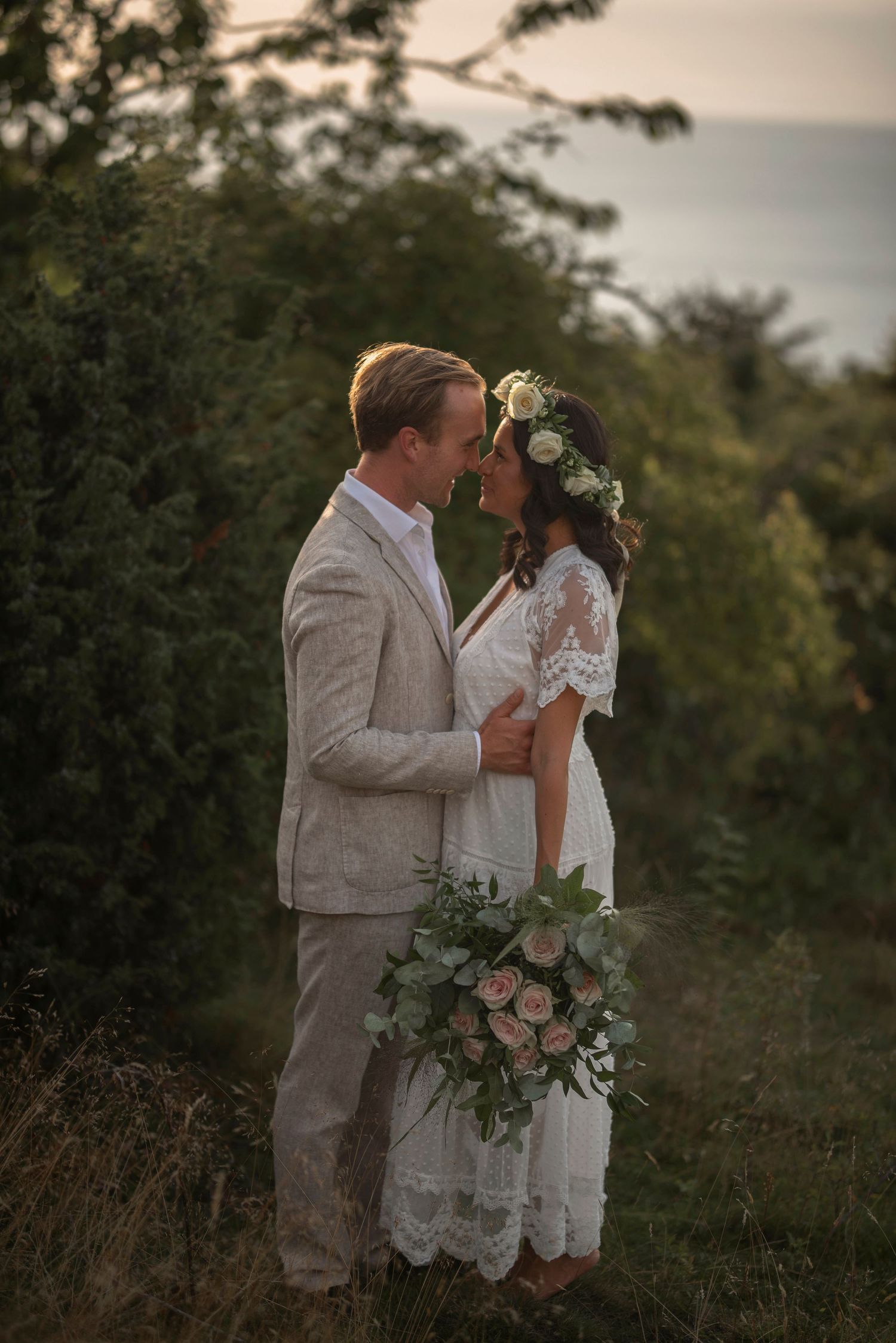 Elopement at Hovs Hallar, Sweden with barefoot bride in floral crown and groom sharing romantic moment on coastal cliffs