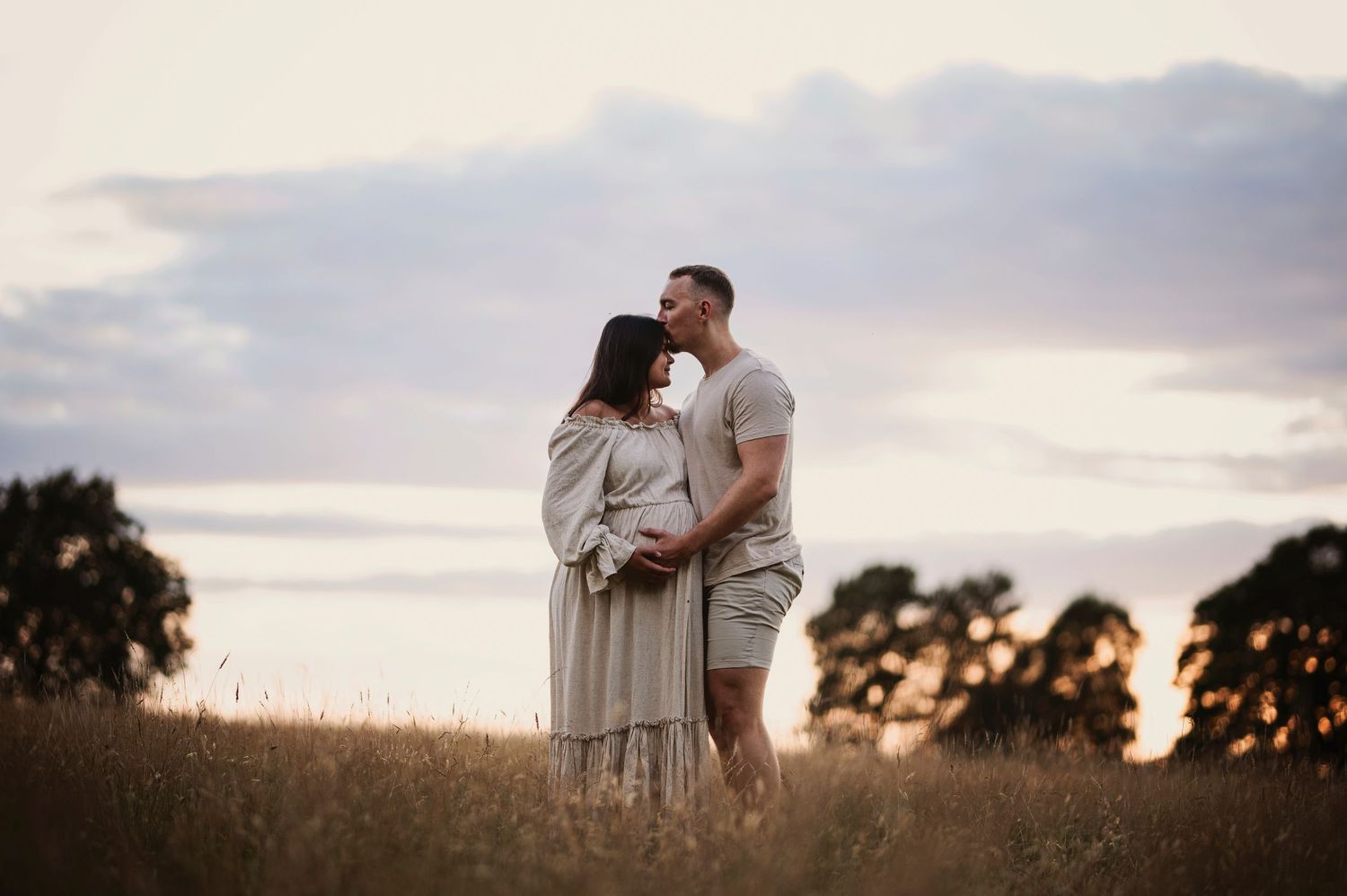 A romantic sunset portrait of a couple embracing in a golden field.