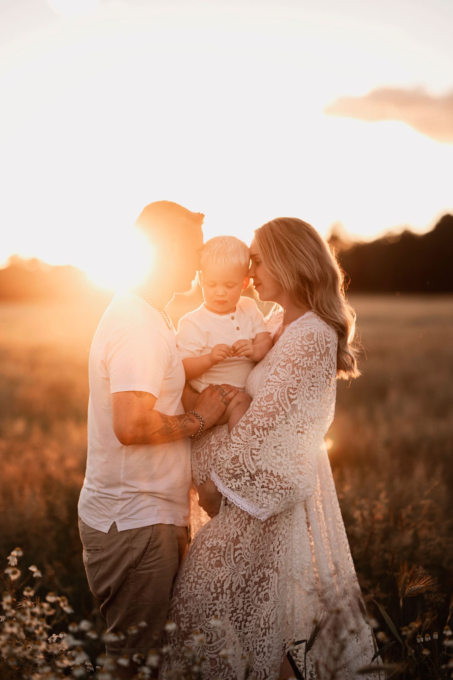 Gravidfotografering i Skåne med blivande föräldrar i gyllene fält i solnedgång med mjukt familjemoment.