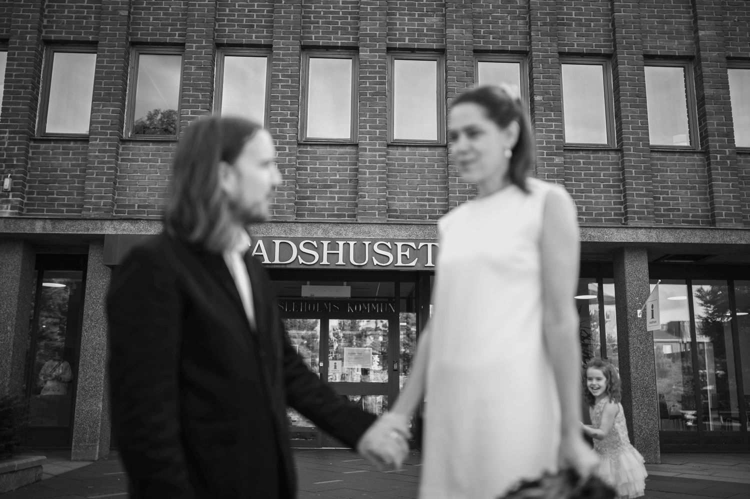 Borgerlig vigsel i Skåne med brudpar som håller hand utanför Stadshuset i svartvitt ljus.