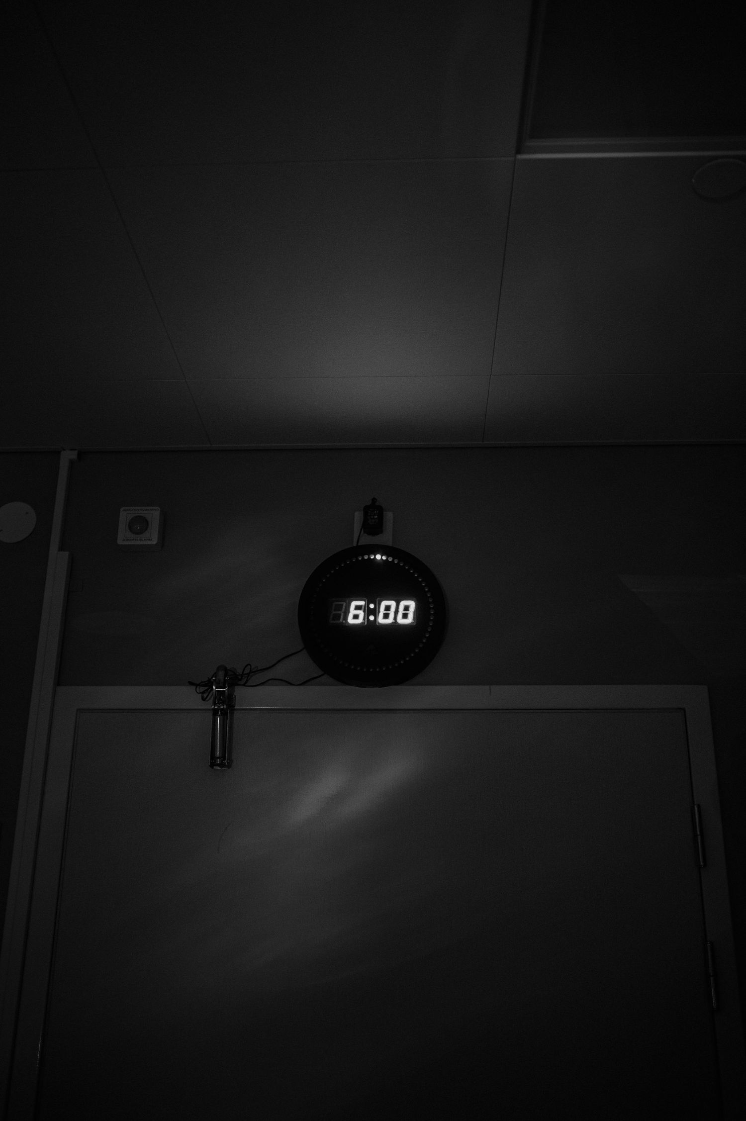 Förlossningsfotografering i Skåne i mörkt sjukhusrum med digital klocka i förlossningsrummet.