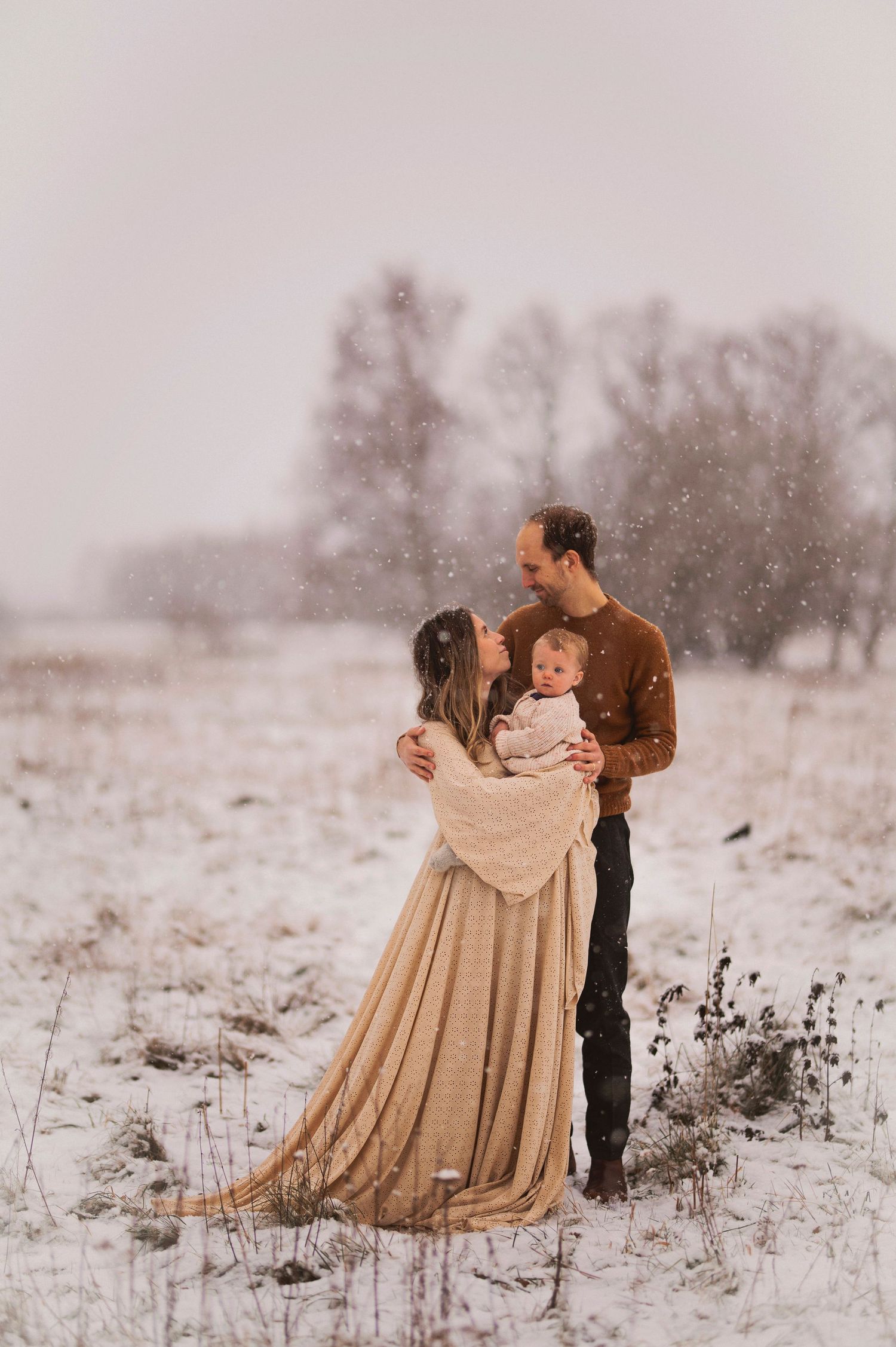 Familjefotografering i Skåne med familj och bebis i snöfall i vinterlandskap.