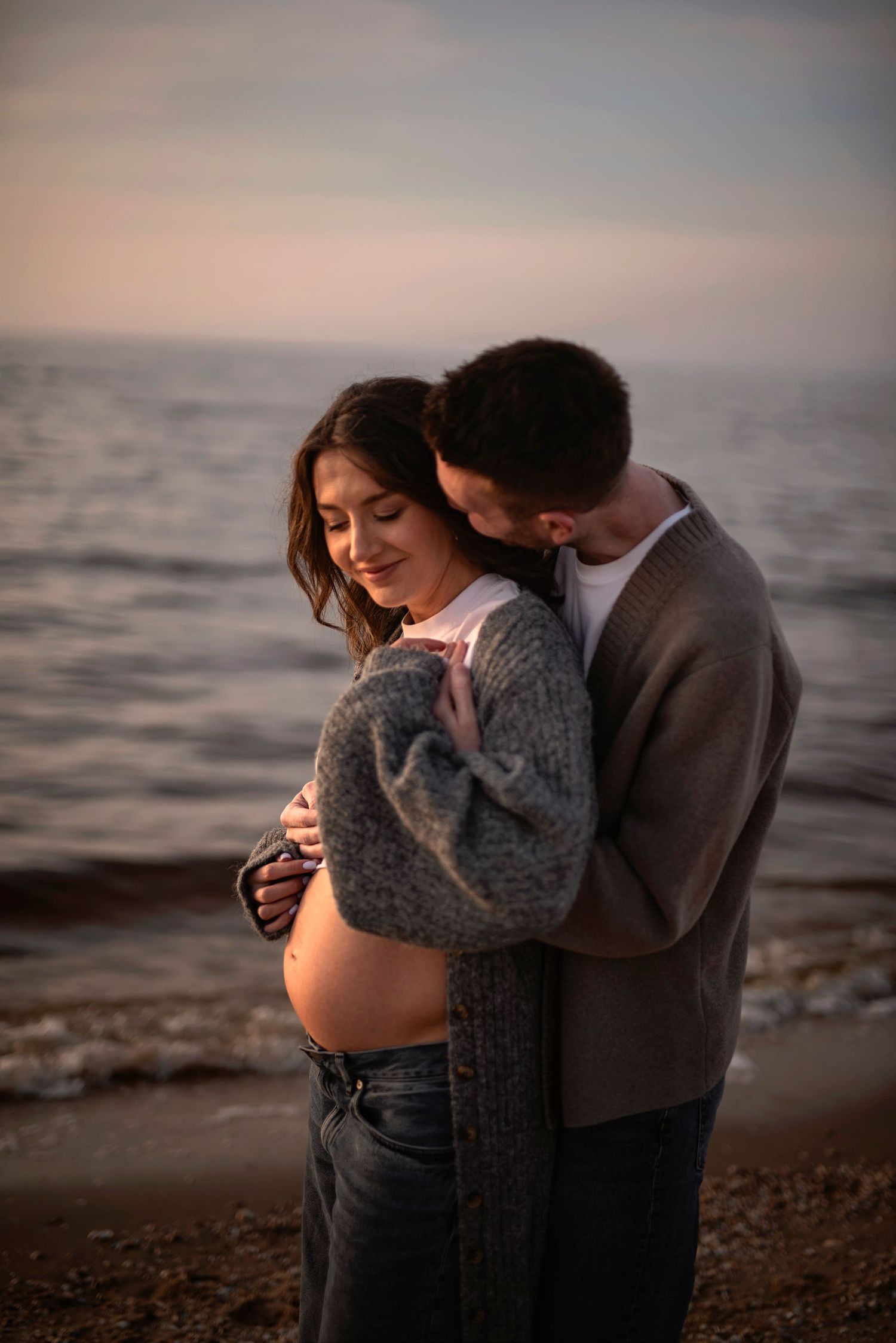 A romantic maternity photoshoot at sunset by the ocean.
