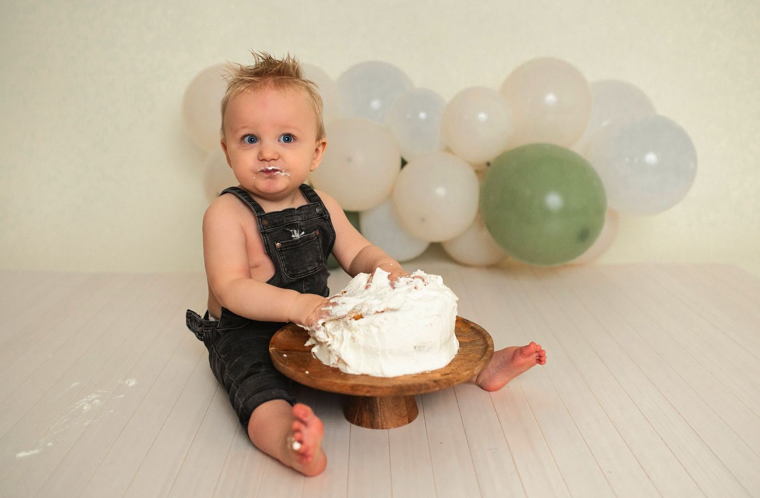 A birthday celebration photoshoot with a white cake and balloon backdrop.