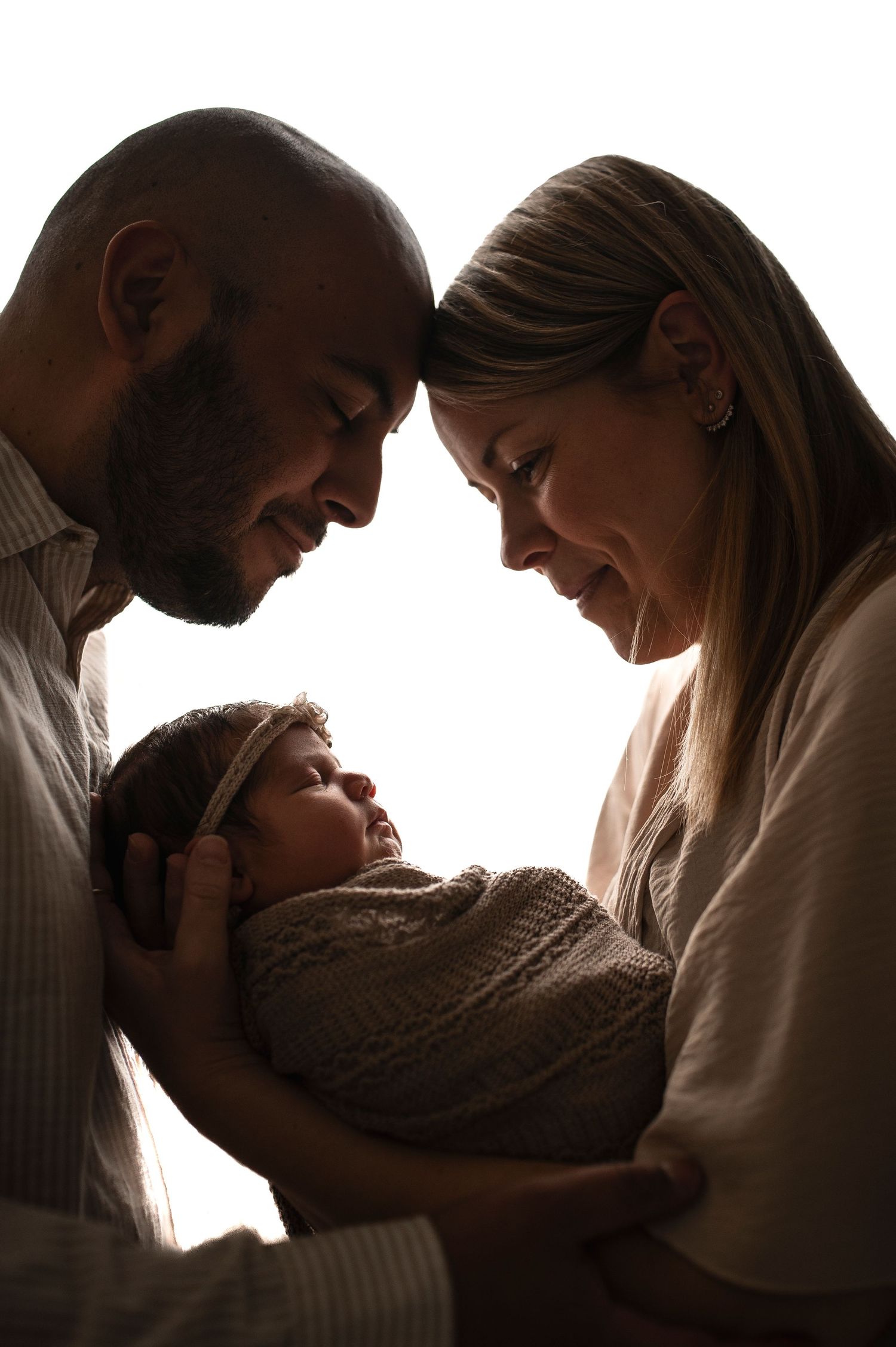 Föräldrar håller sin nyfödda bebis i famnen under en nyföddfotografering i Hässleholm.