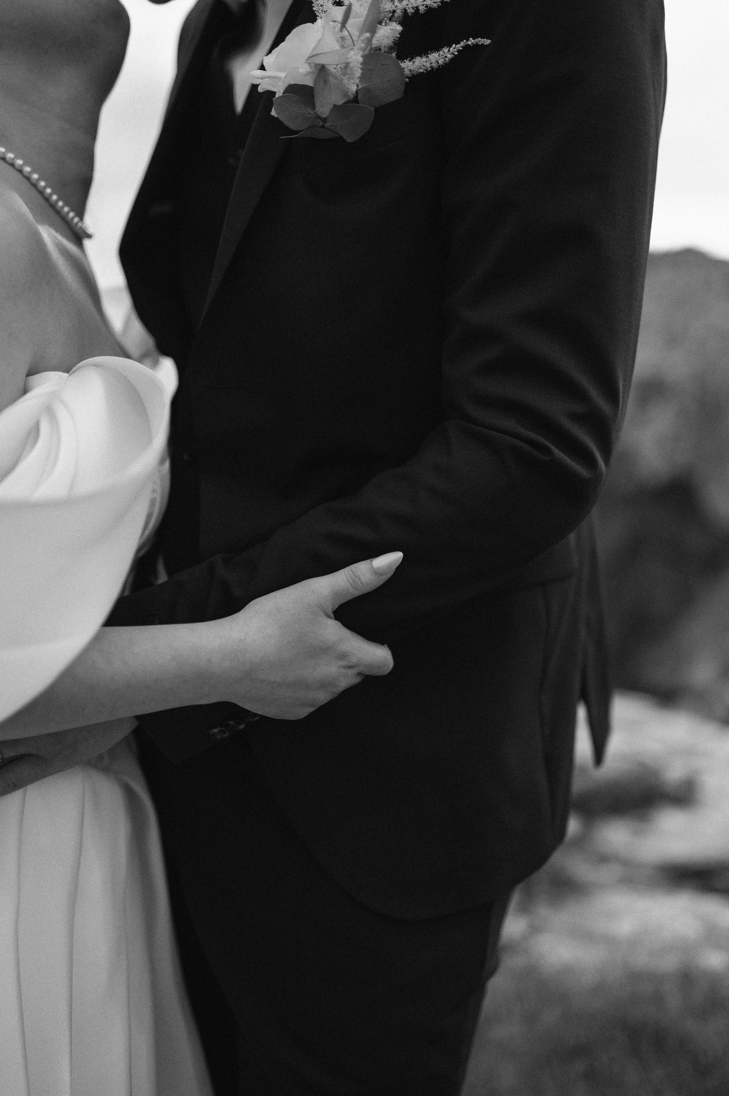 Black and white wedding photo of bride and groom holding hands, groom in dark suit with boutonniere. Kullaberg elopment