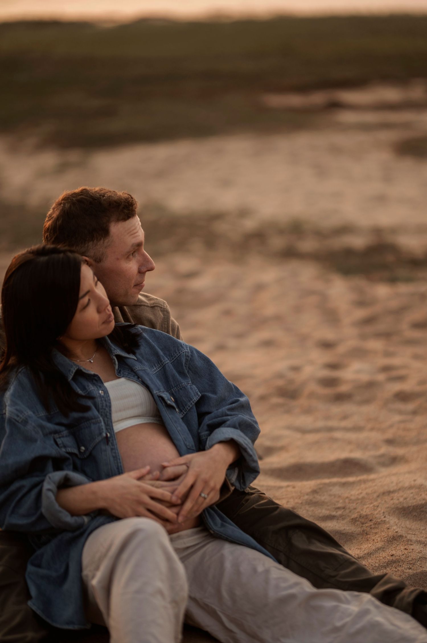 Gravidfotografering i Skåne med blivande föräldrar på stranden i gyllene kvällsljus