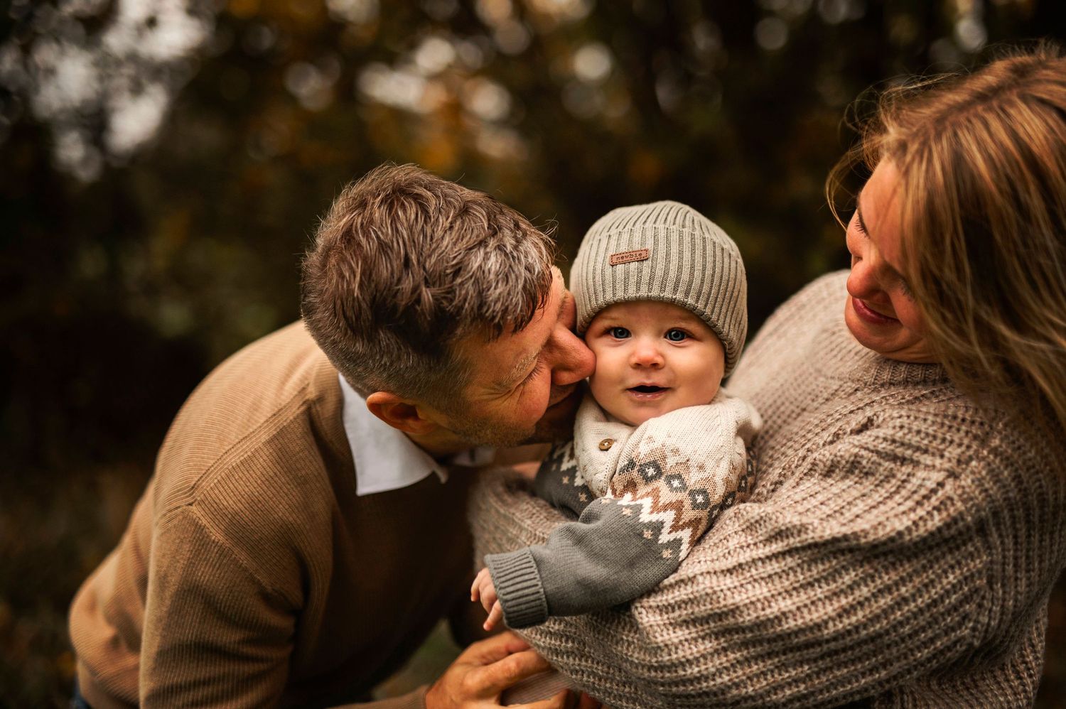 Intimate family portrait outdoors with warm autumn colors and cozy knit sweaters.