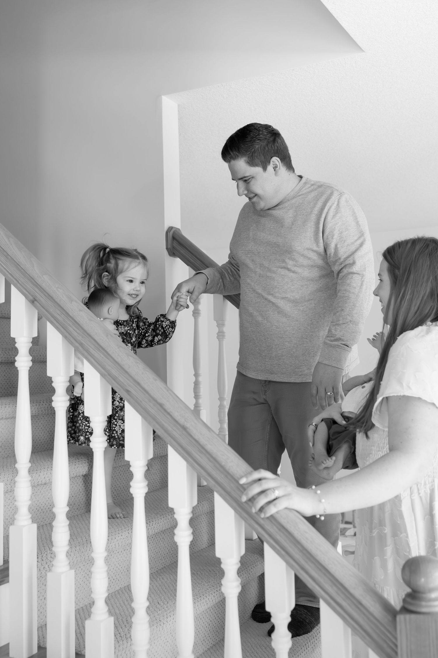 Black and white photo of a father and daughter on a staircase at home.