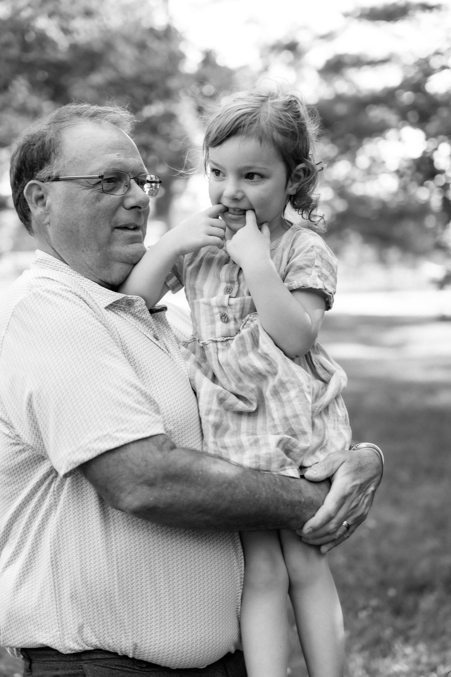 Black and white photo of grandfather holding a young child in an outdoor park.