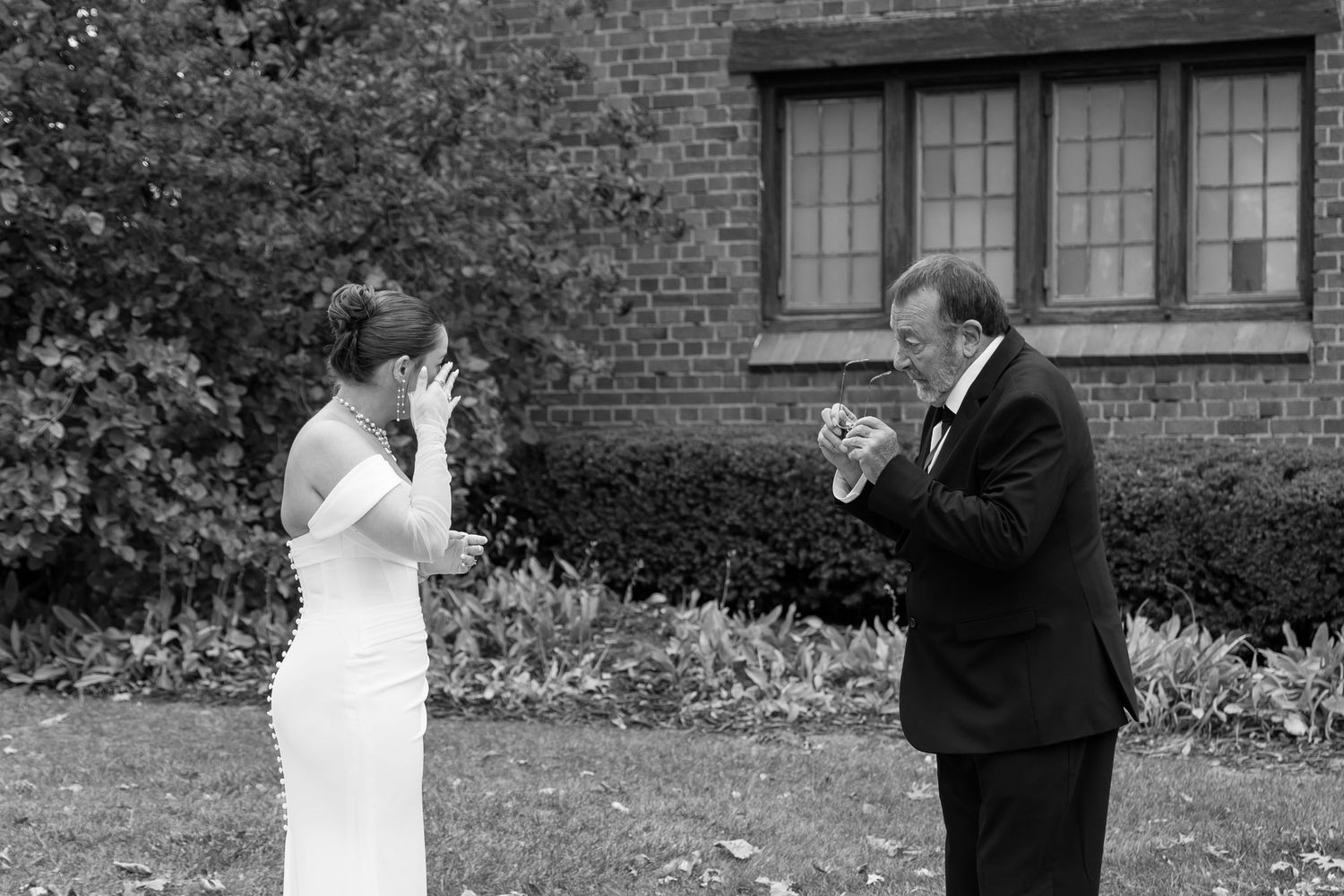 Black and white photo of a bride and groom sharing an emotional first look moment outdoors.