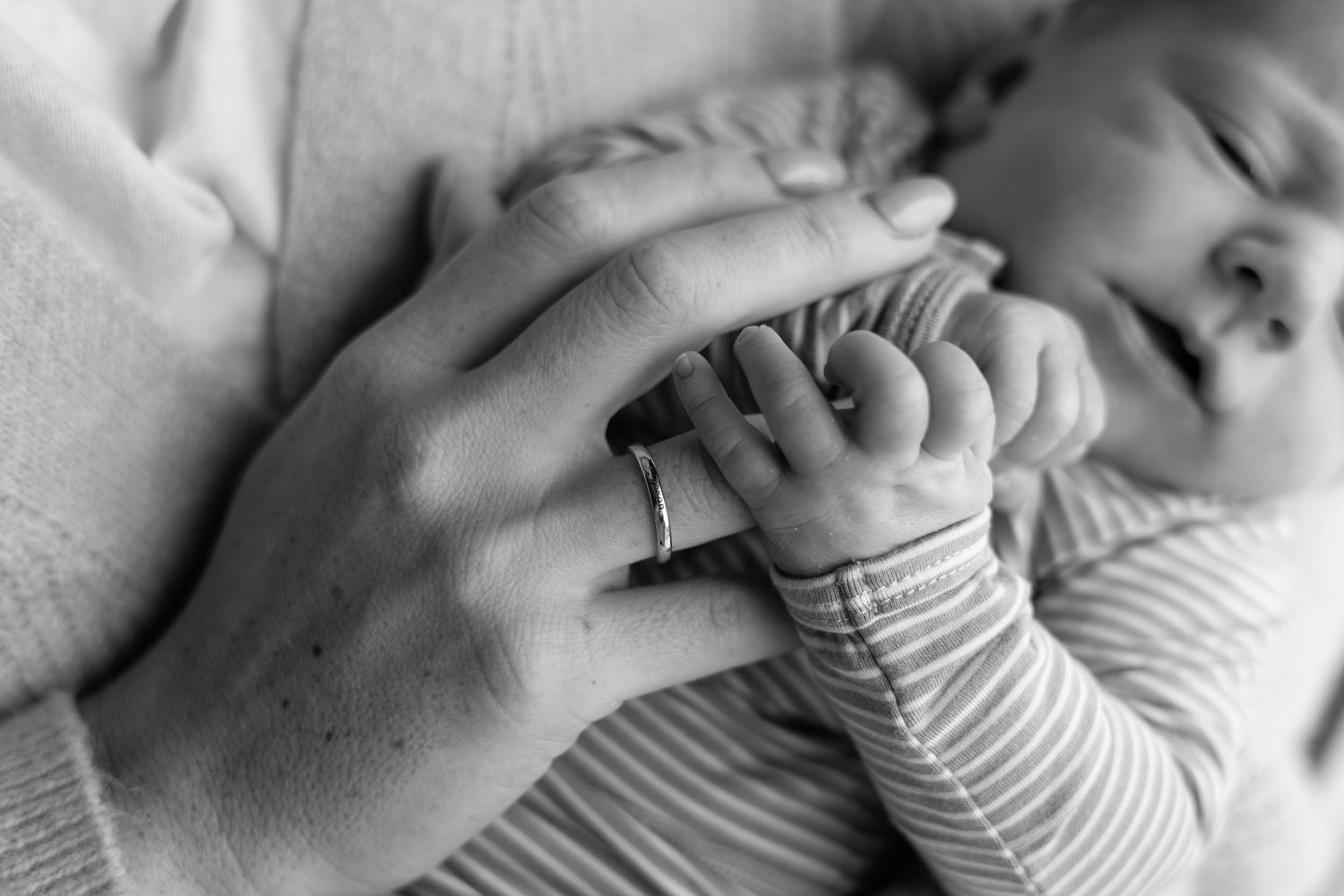 Black and white close-up of newborn baby grasping parent's finger.