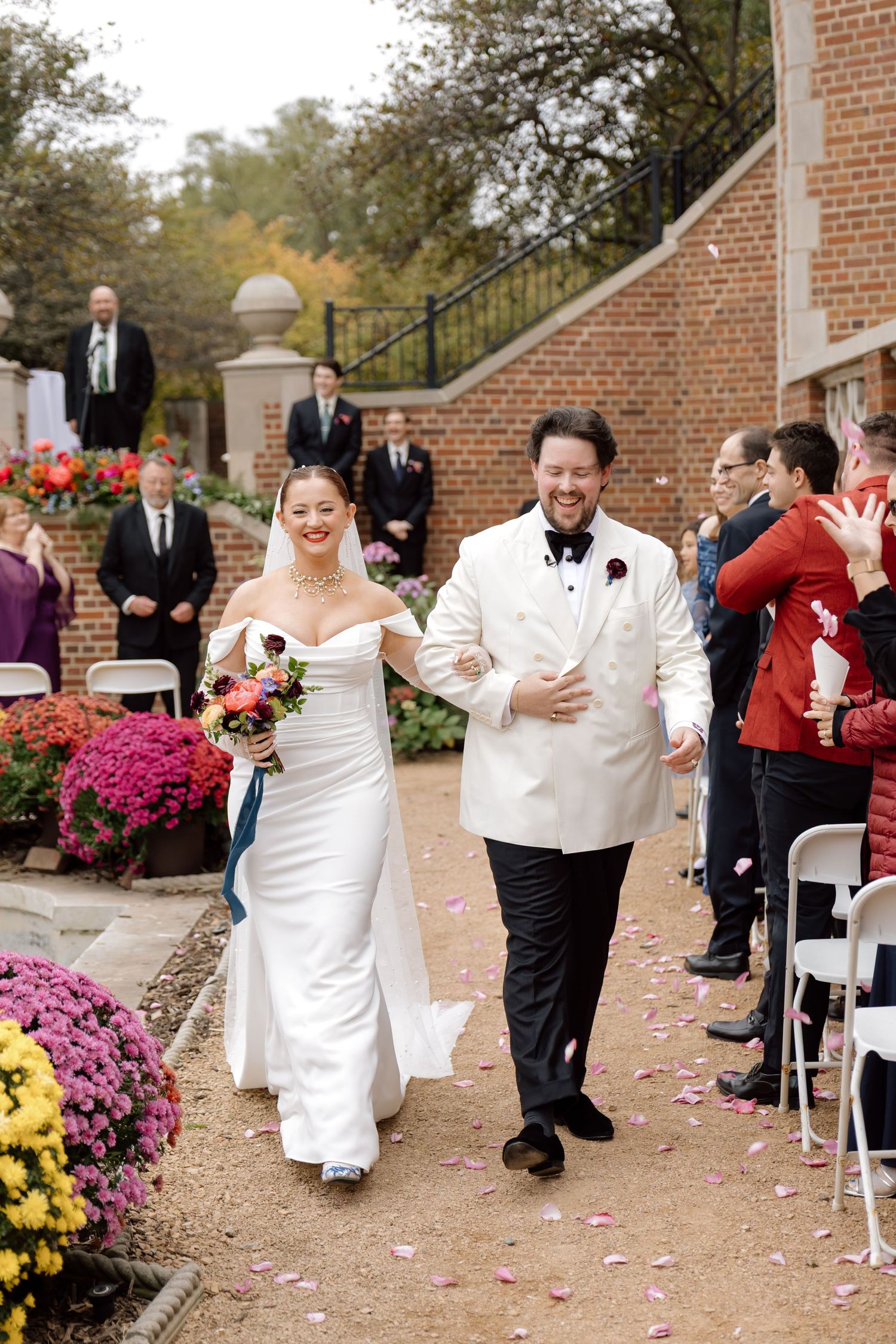 Joyful bride and groom walk back down the aisle after outdoor fall wedding ceremony.