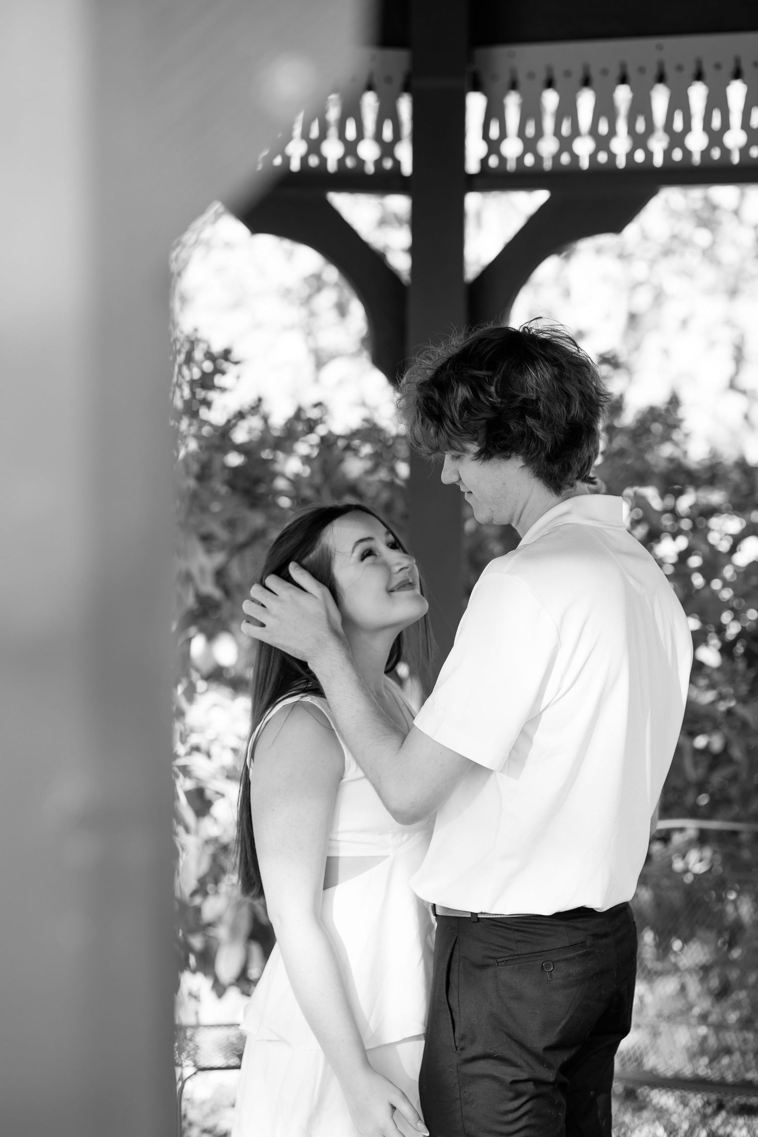 Black and white romantic moment of couple gazing at each other under gazebo.