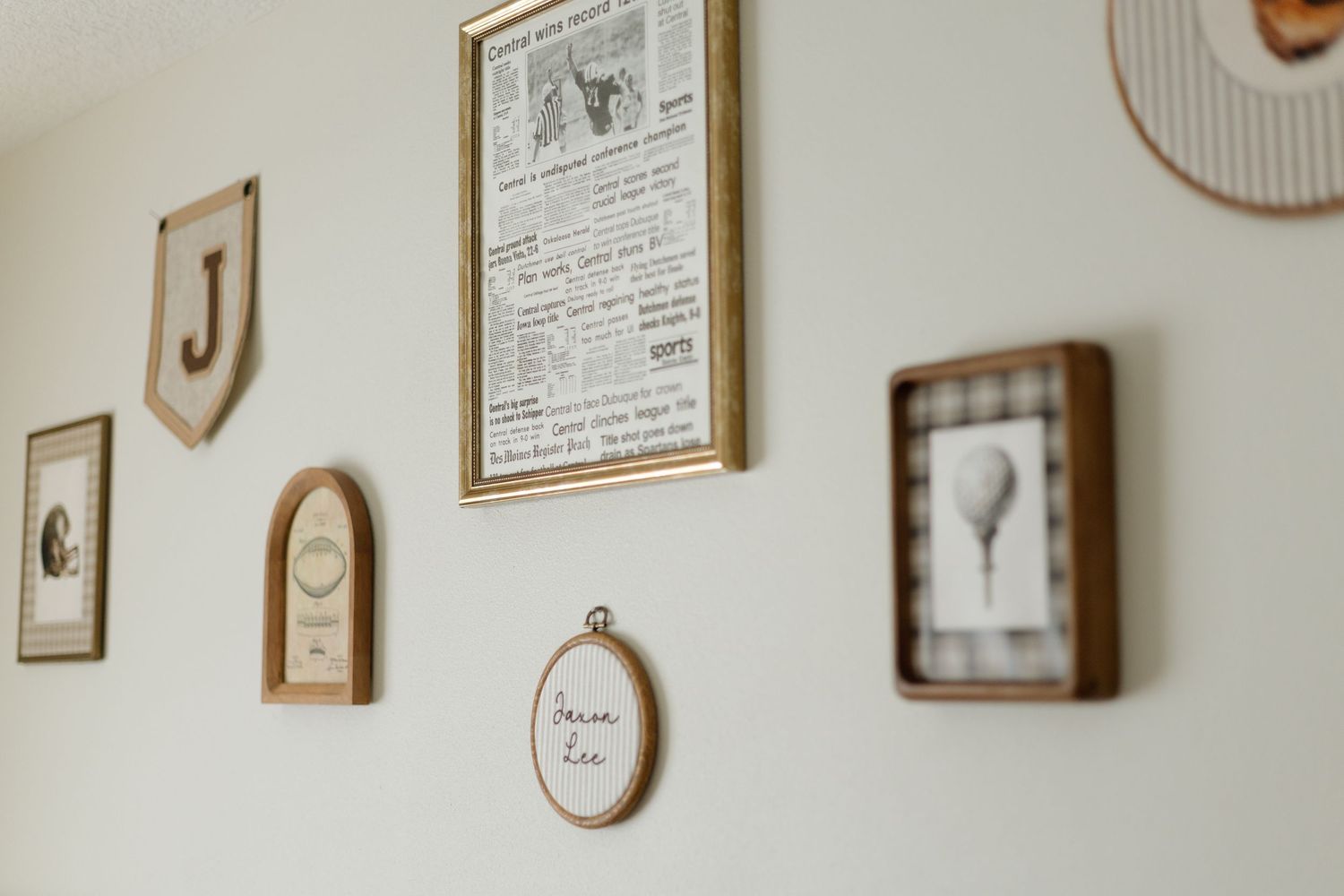 Nursery gallery wall featuring framed prints, wooden letters, and embroidered hoop art decor.