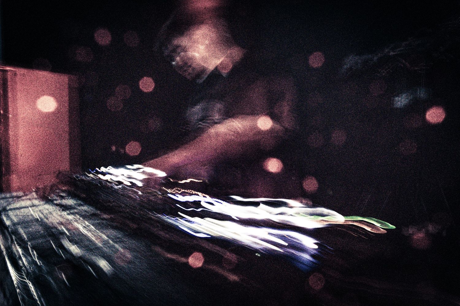 DJ hands mixing tracks on turntables in a dark club with bokeh lights in the background.