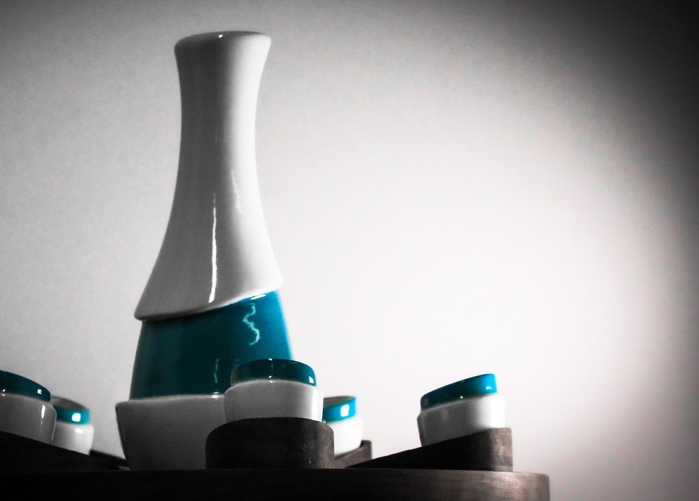 Modern turquoise and white ceramic sake set with minimalist design on dark base.