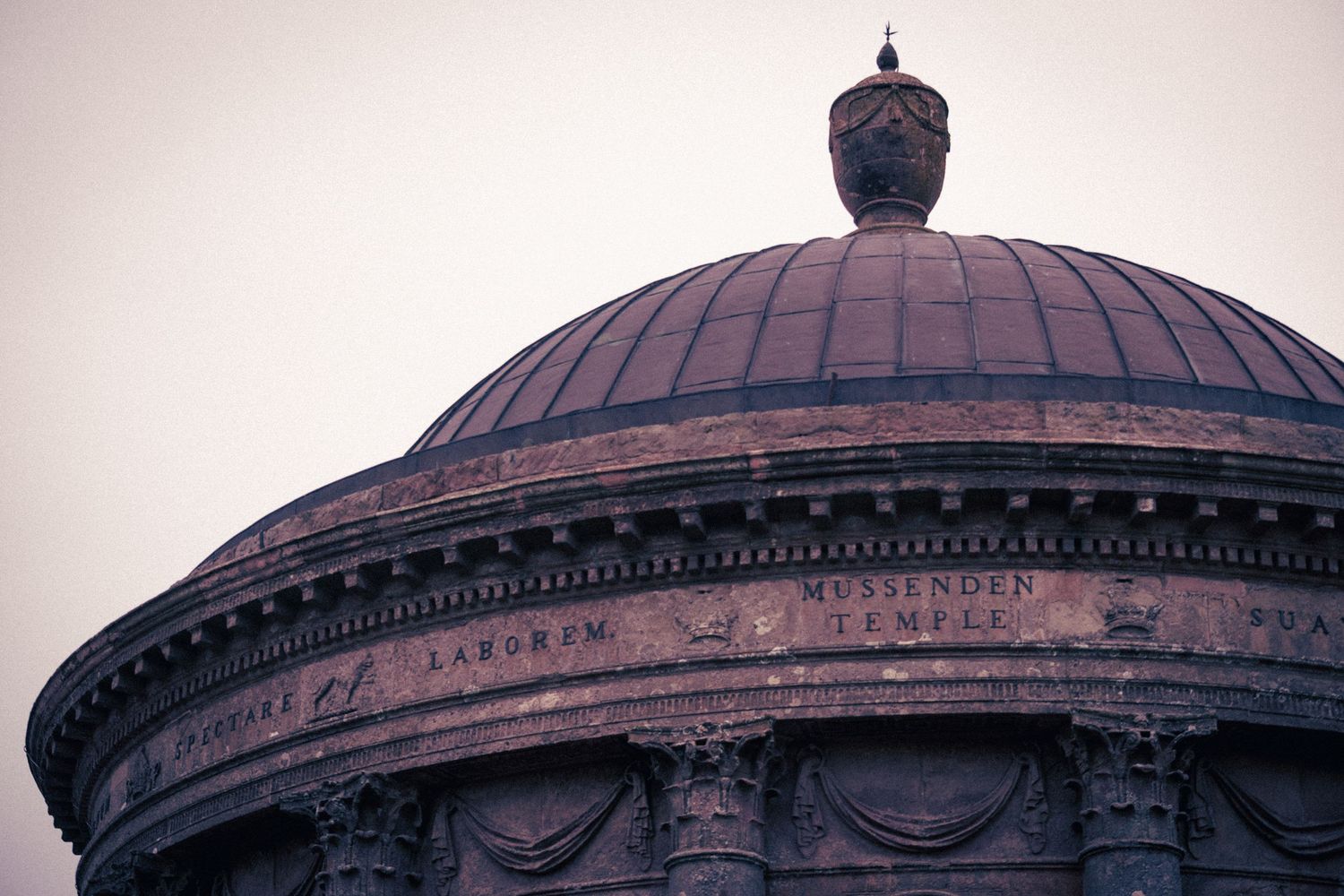 Close-up of an ornate domed building with classical architecture and carved inscriptions on the stone facade.