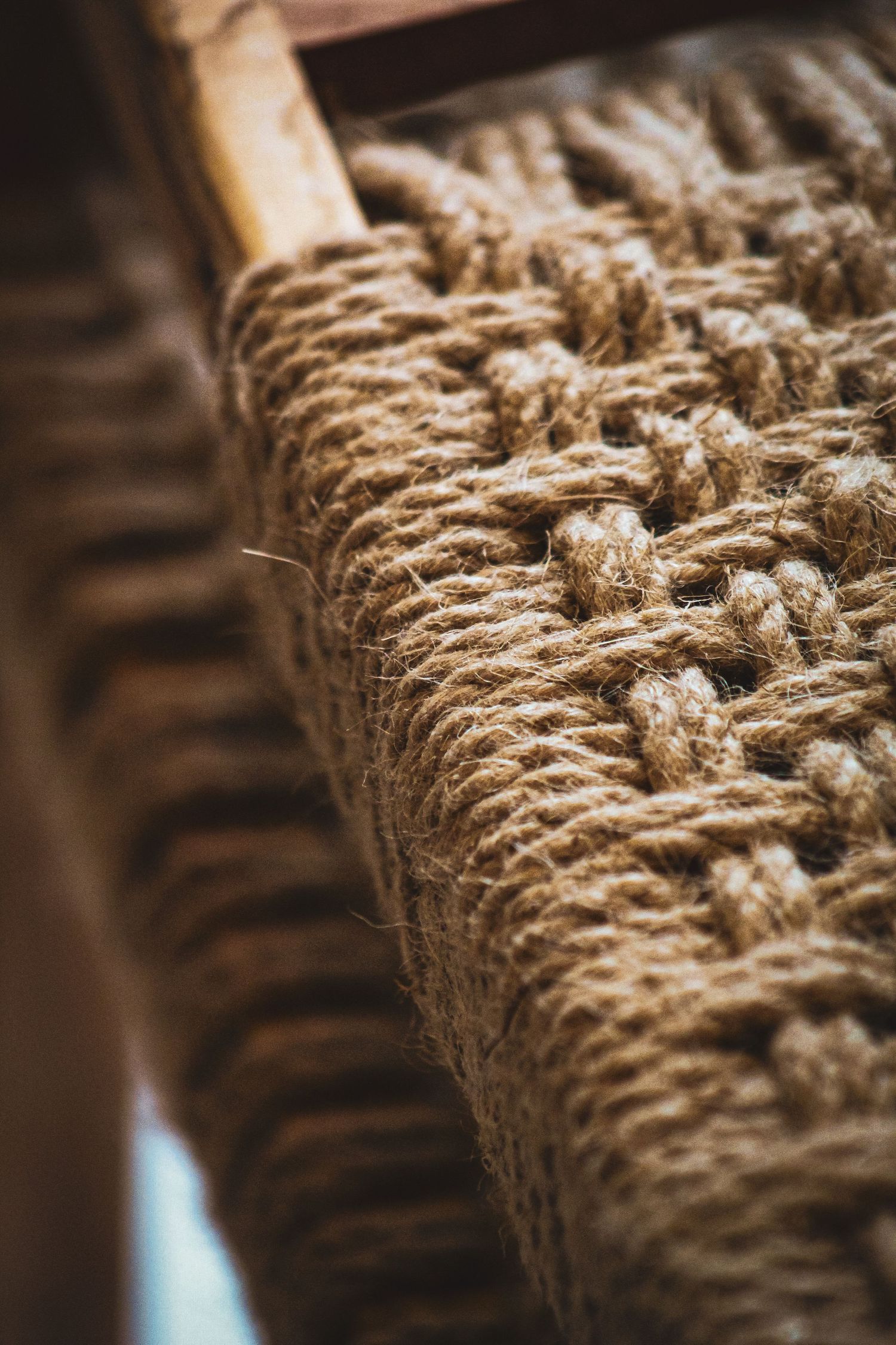 Close-up of a woven jute rope chair seat with natural fiber texture and wooden frame detail.