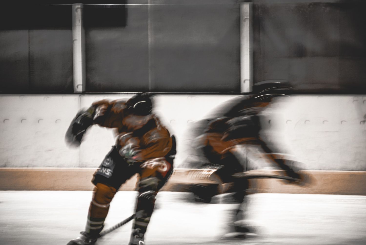 Two ice hockey players in motion blur during an intense game, wearing full protective gear on an indoor rink.