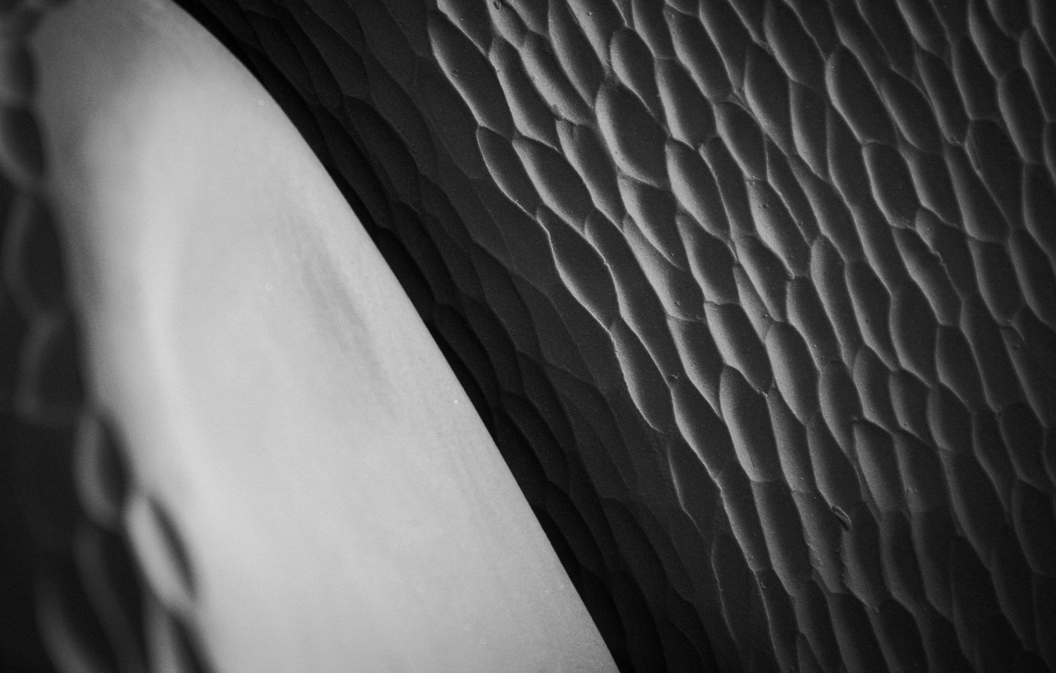 Close-up black and white texture of geometric diamond pattern surface with smooth curve.