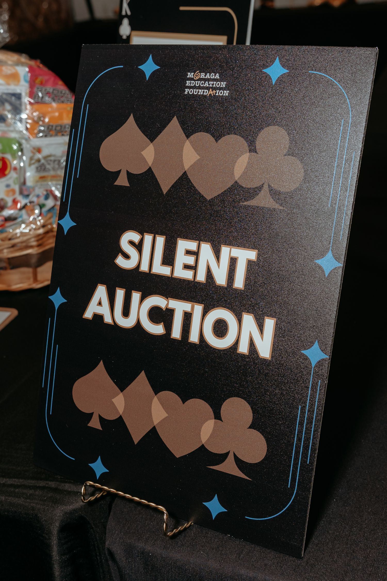 A series of dark signs with the text 'SILENT AUCTION' displayed at an event with blue star decorative elements.
